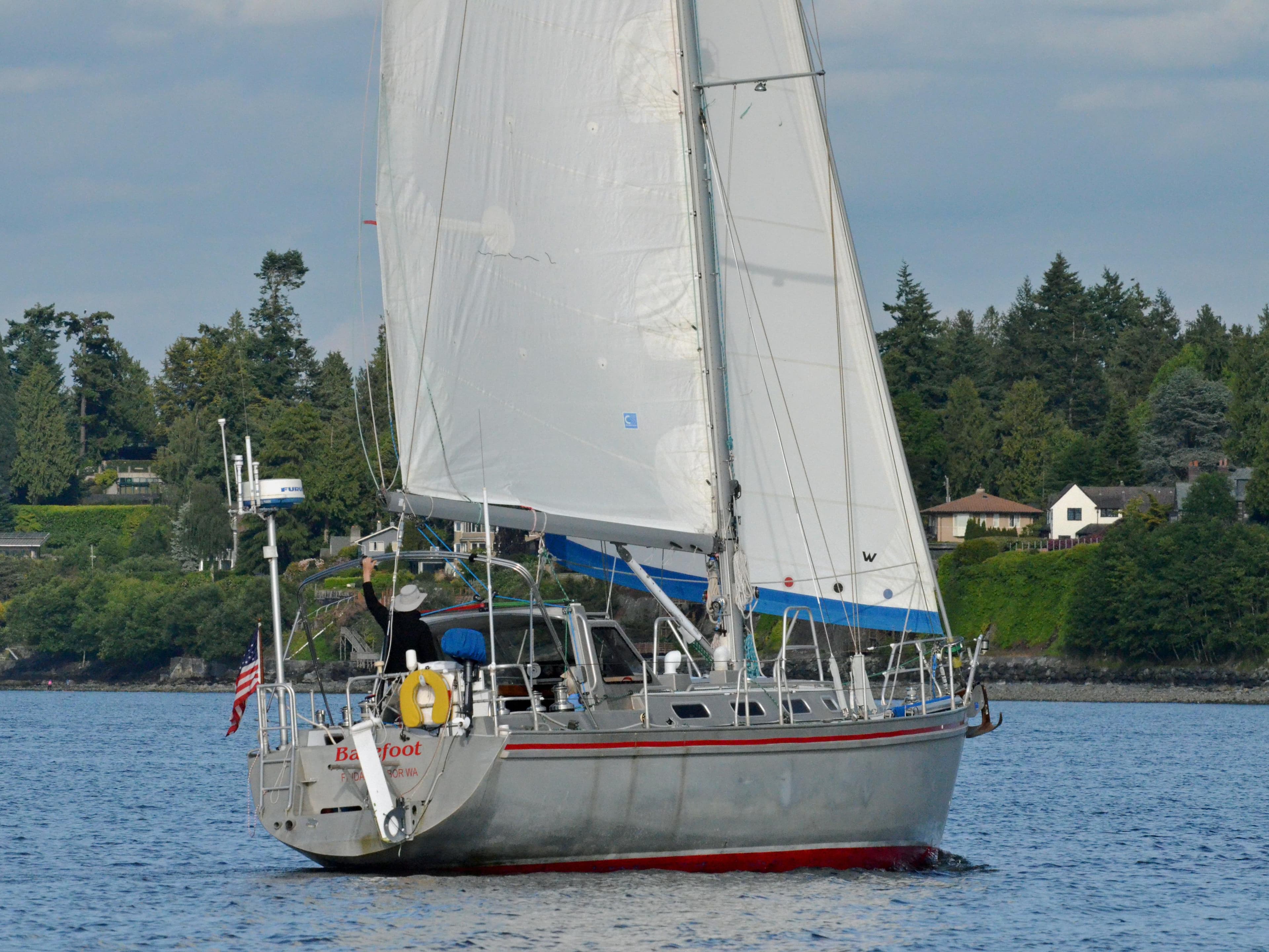 Sailing yacht Lavranos 43, 2010 model, cruising on calm waters near a forested shoreline.