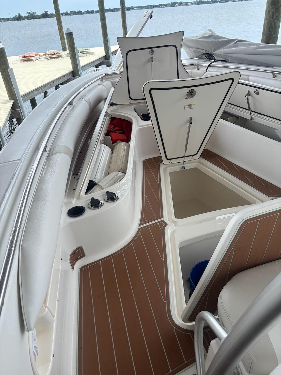 2006 Boston Whaler 320 Outrage boat interior with open storage compartments and wood-patterned flooring.
