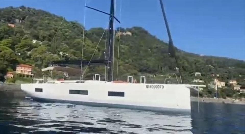 2023 Solaris 50 yacht sailing near a lush, green coastline.