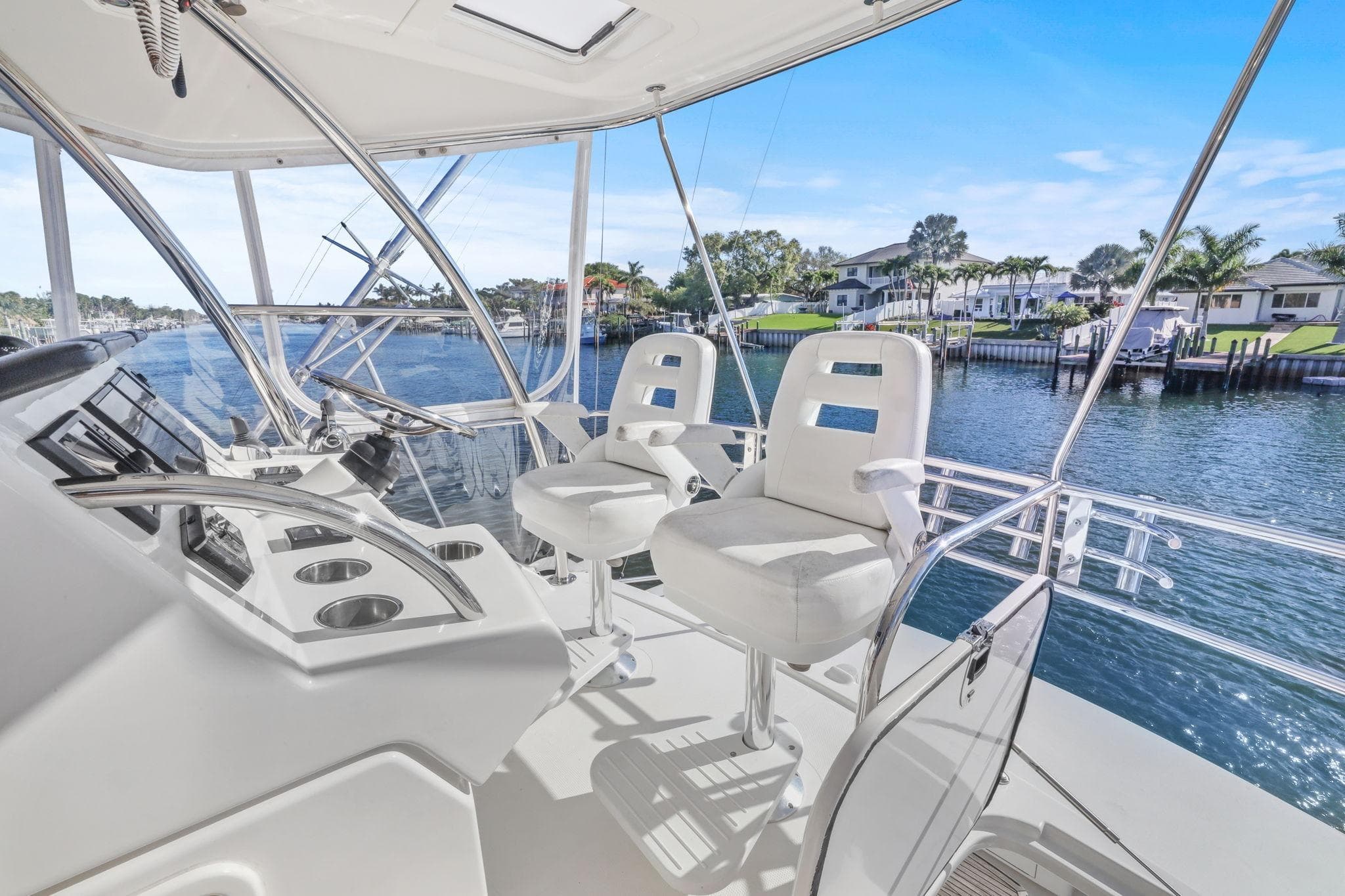 Flybridge of 2016 Riviera 43 Open, featuring helm chairs and waterfront view.