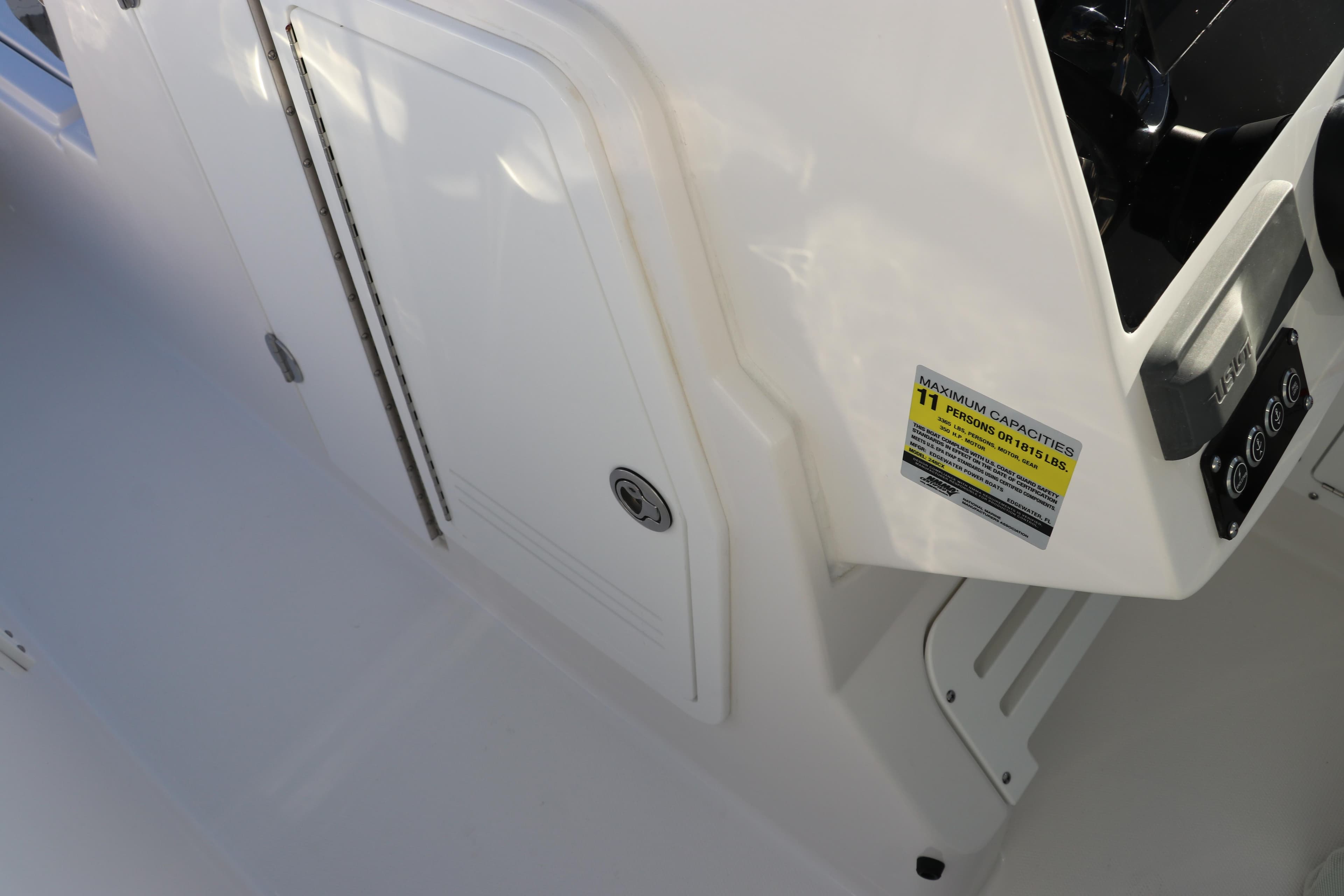 Edgewater 248 CX 2025 boat interior with storage compartment and control panel.
