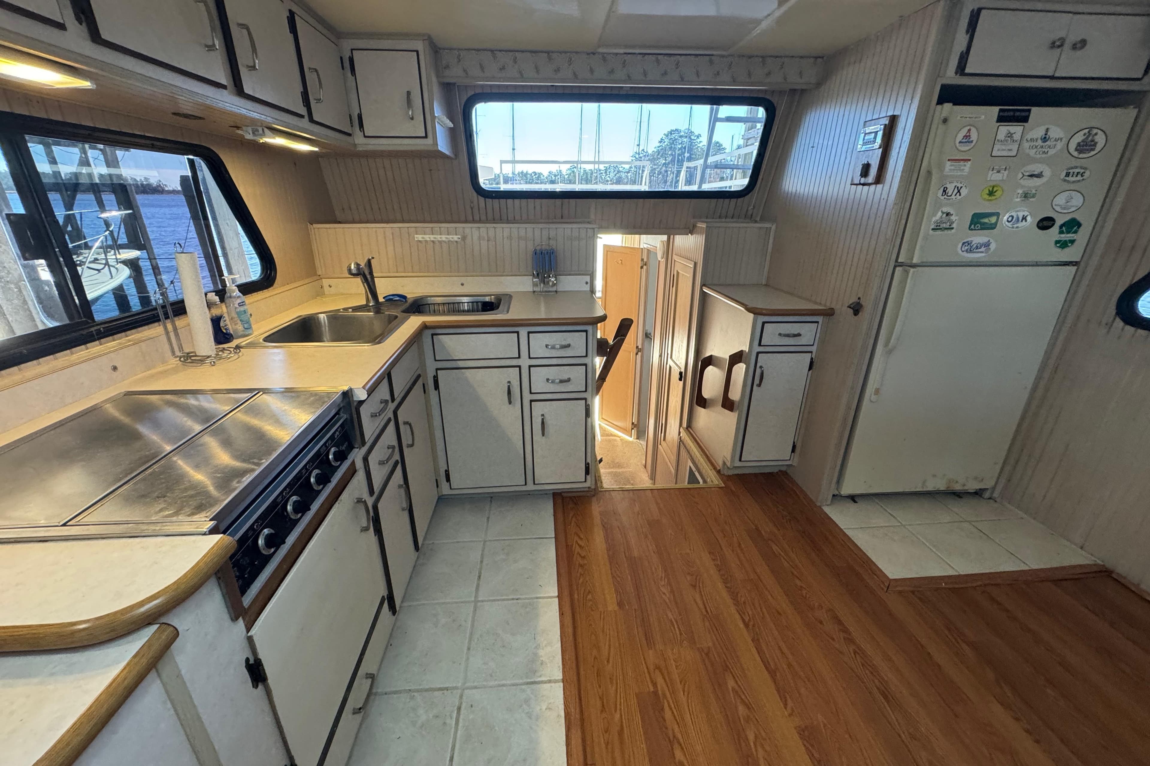 1999 Gibson Houseboat 50 kitchen with white cabinets, stove, sink, and large windows.