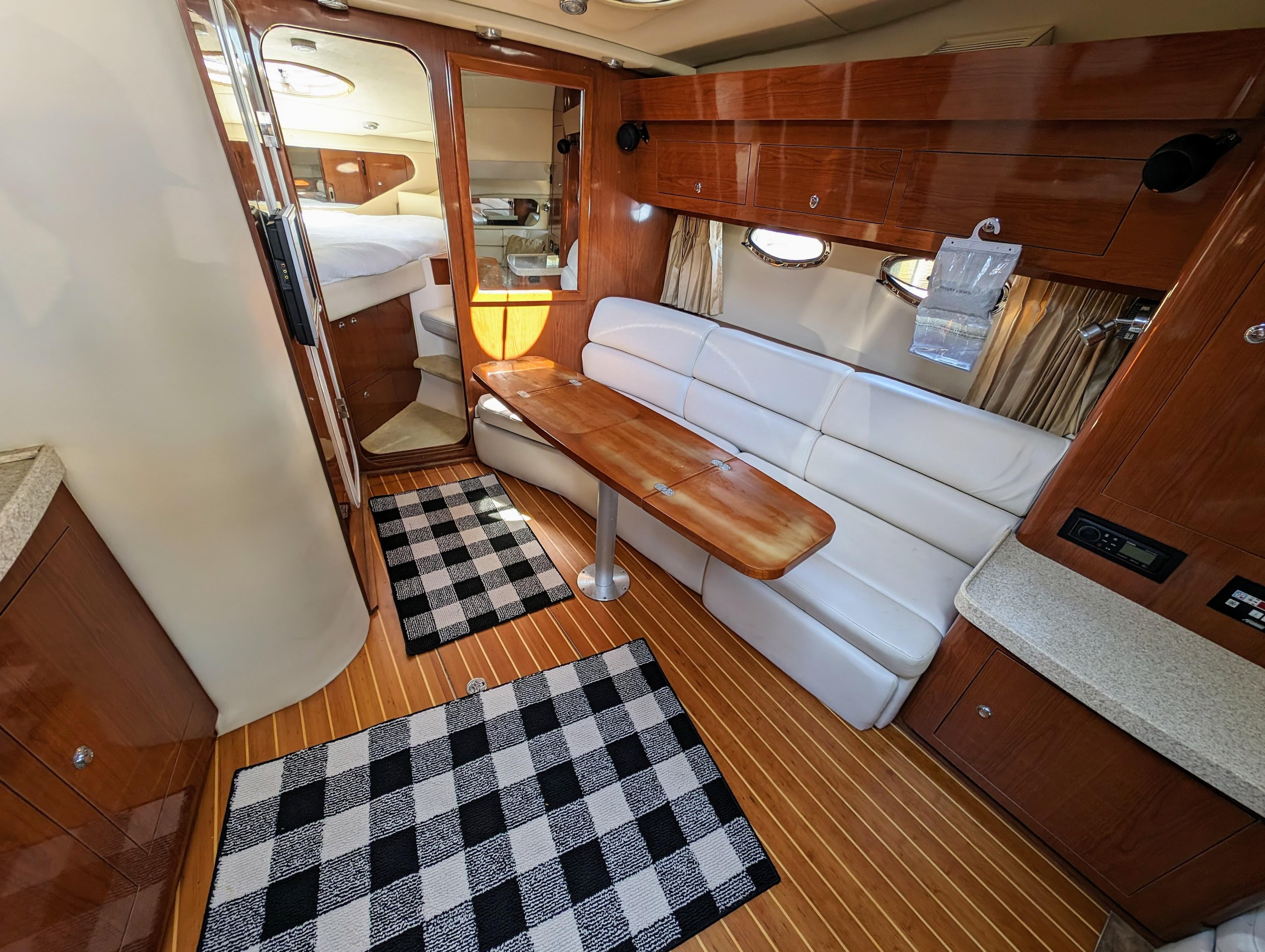Interior of 2005 Regal 3560 yacht with wood accents, white seating, and checkered rugs.