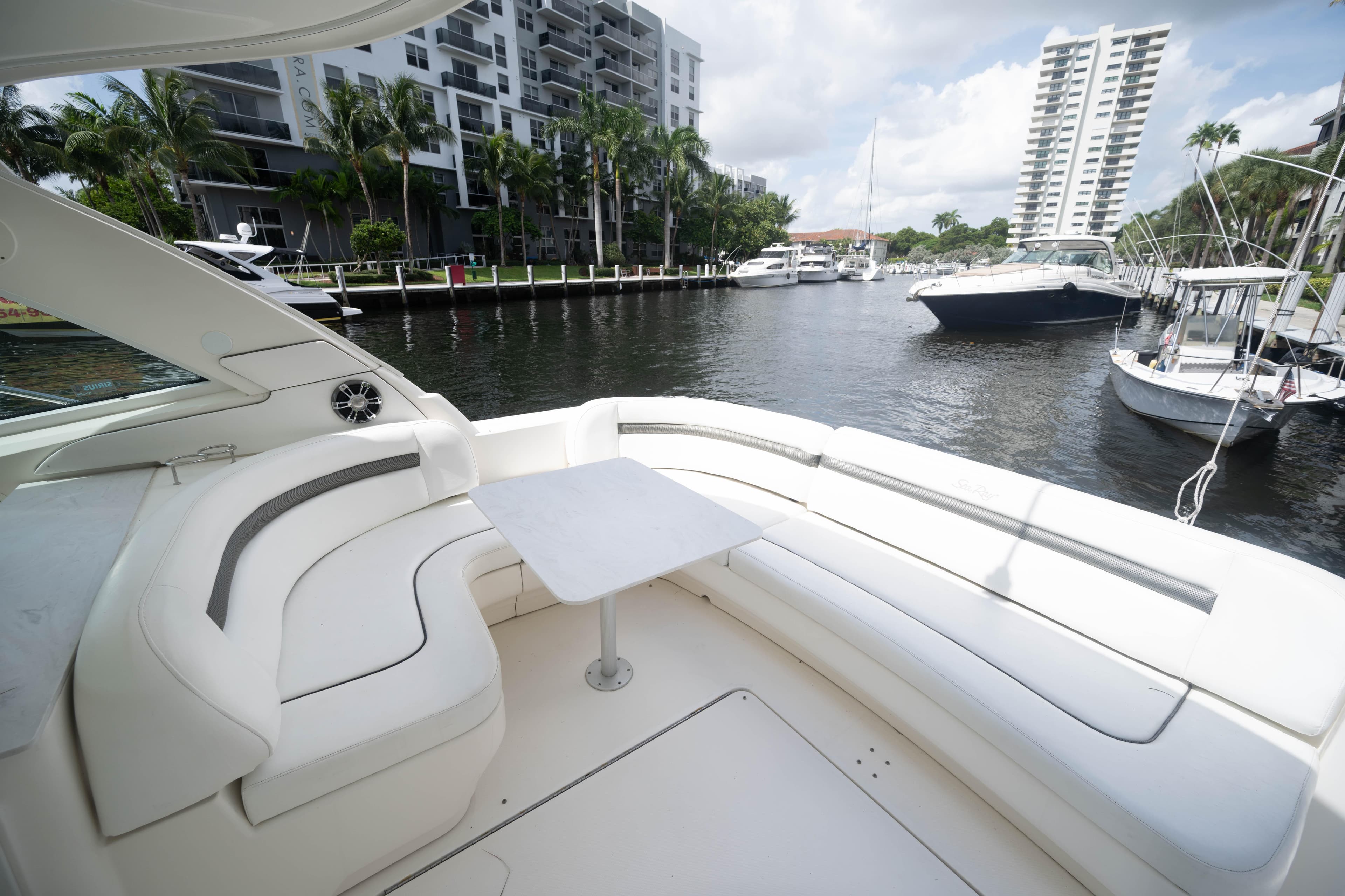 2006 Sea Ray 48 Sundancer yacht with spacious seating, docked near waterfront buildings.