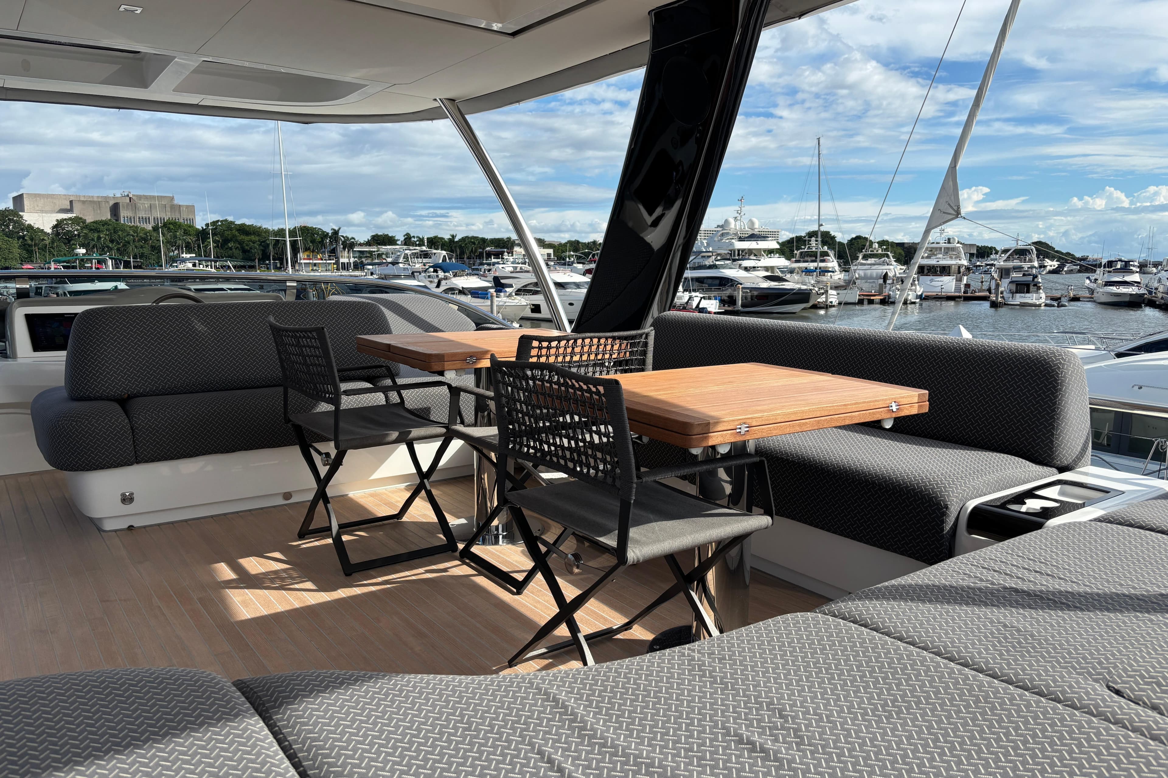 Luxurious 2023 Lagoon SIXTY 7 yacht deck with seating, tables, and marina view.