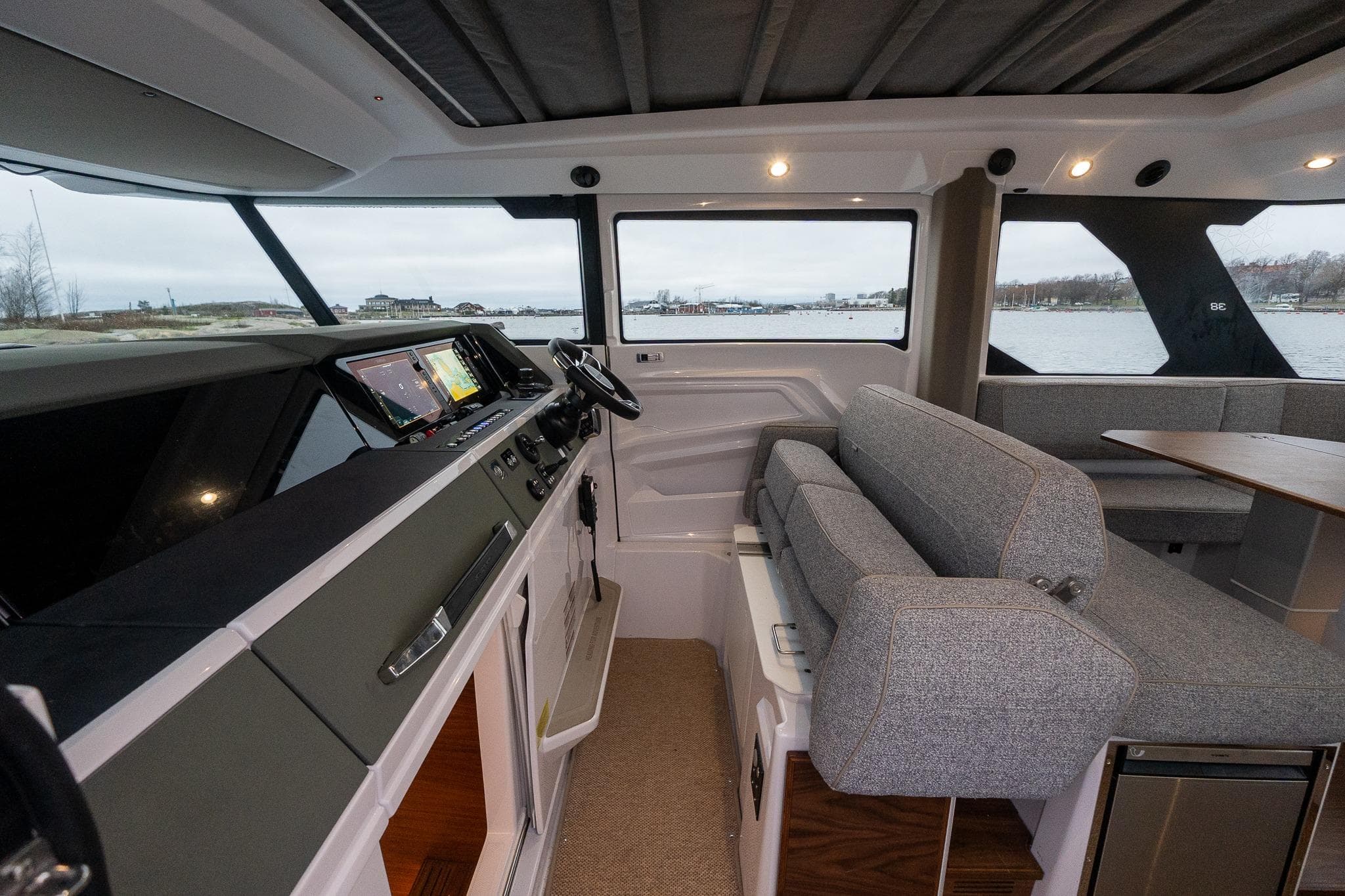 2027 Axopar 38 Cross Cabin interior with modern helm and seating, overlooking water.