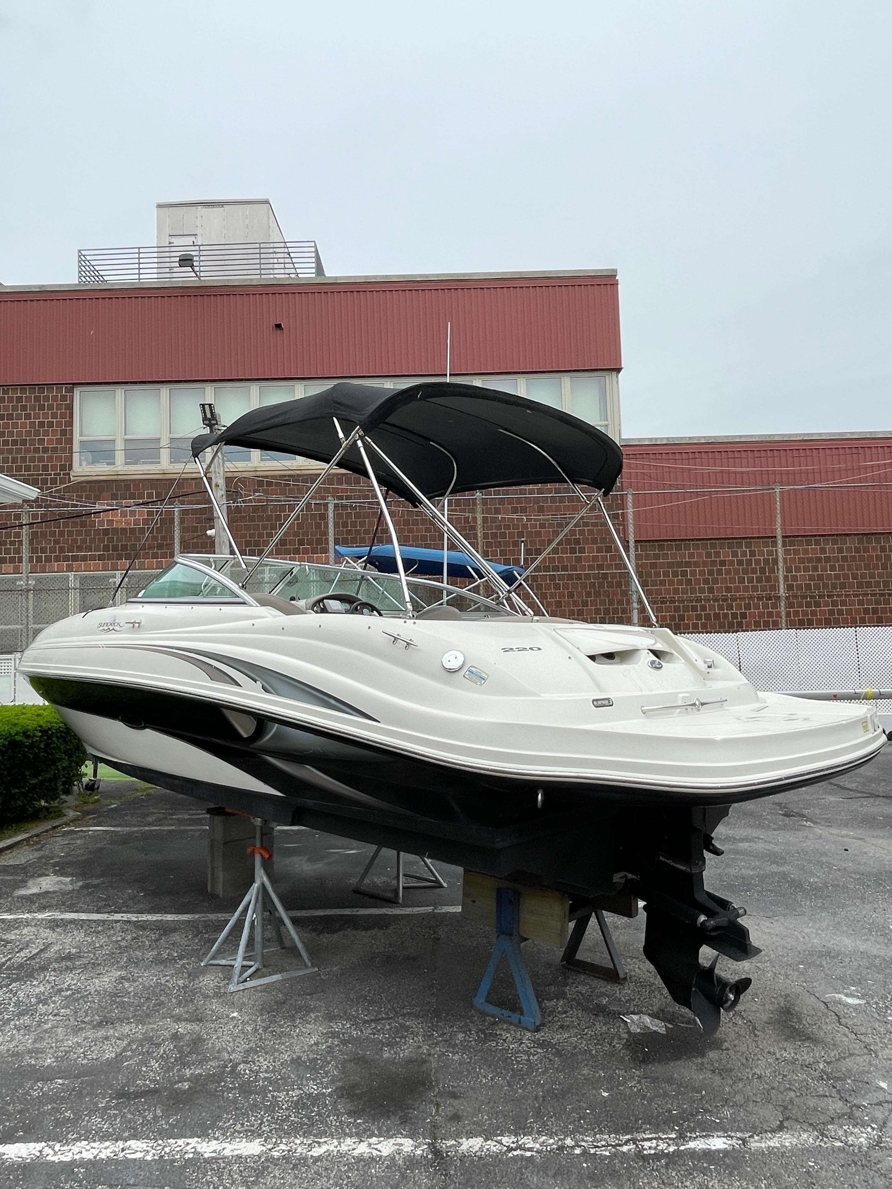 2004 Sea Ray 220 Sundeck boat on stands, with canopy, in a parking lot.