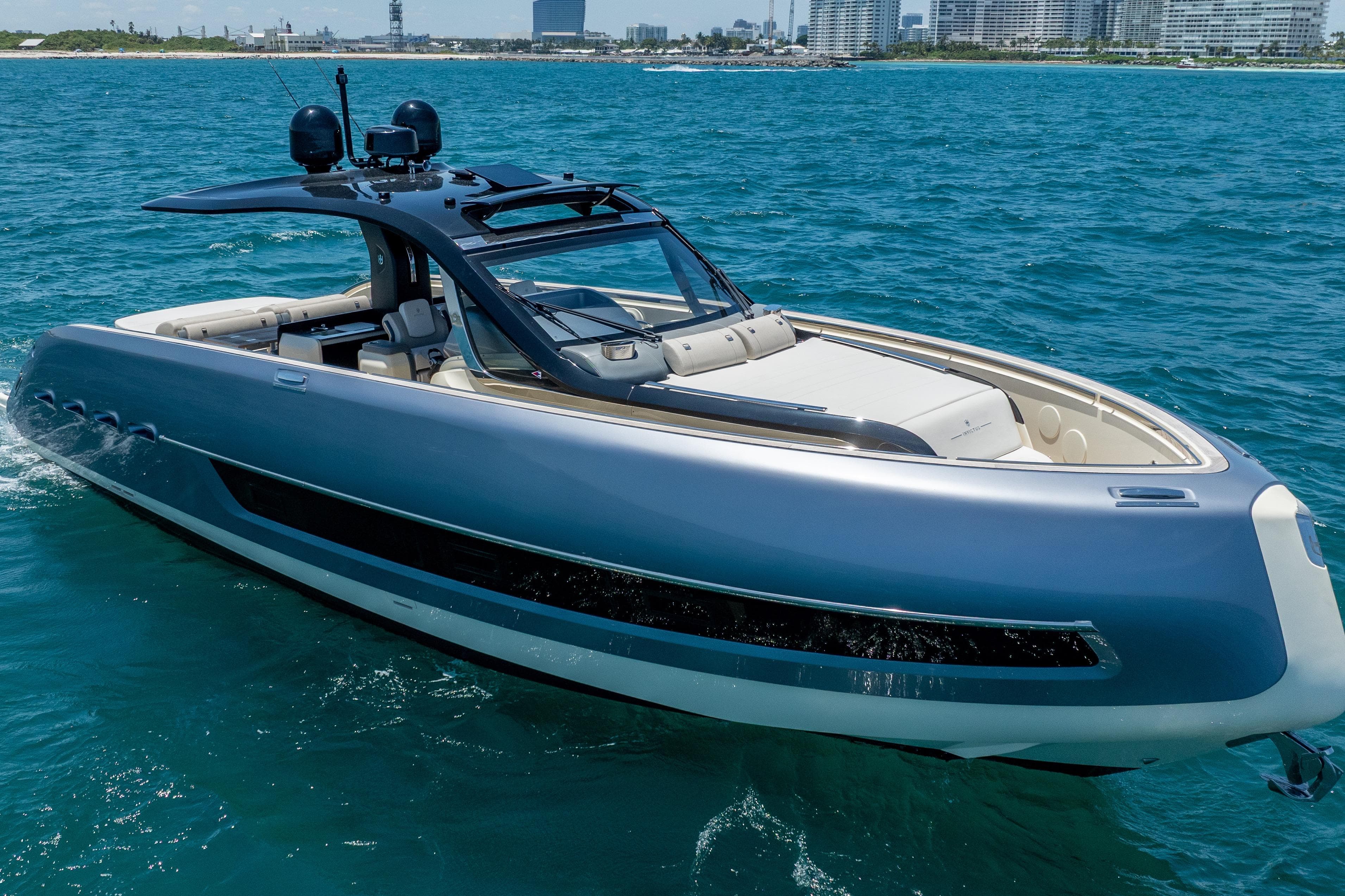 2024 Invictus TT460 yacht cruising on blue ocean near city skyline.