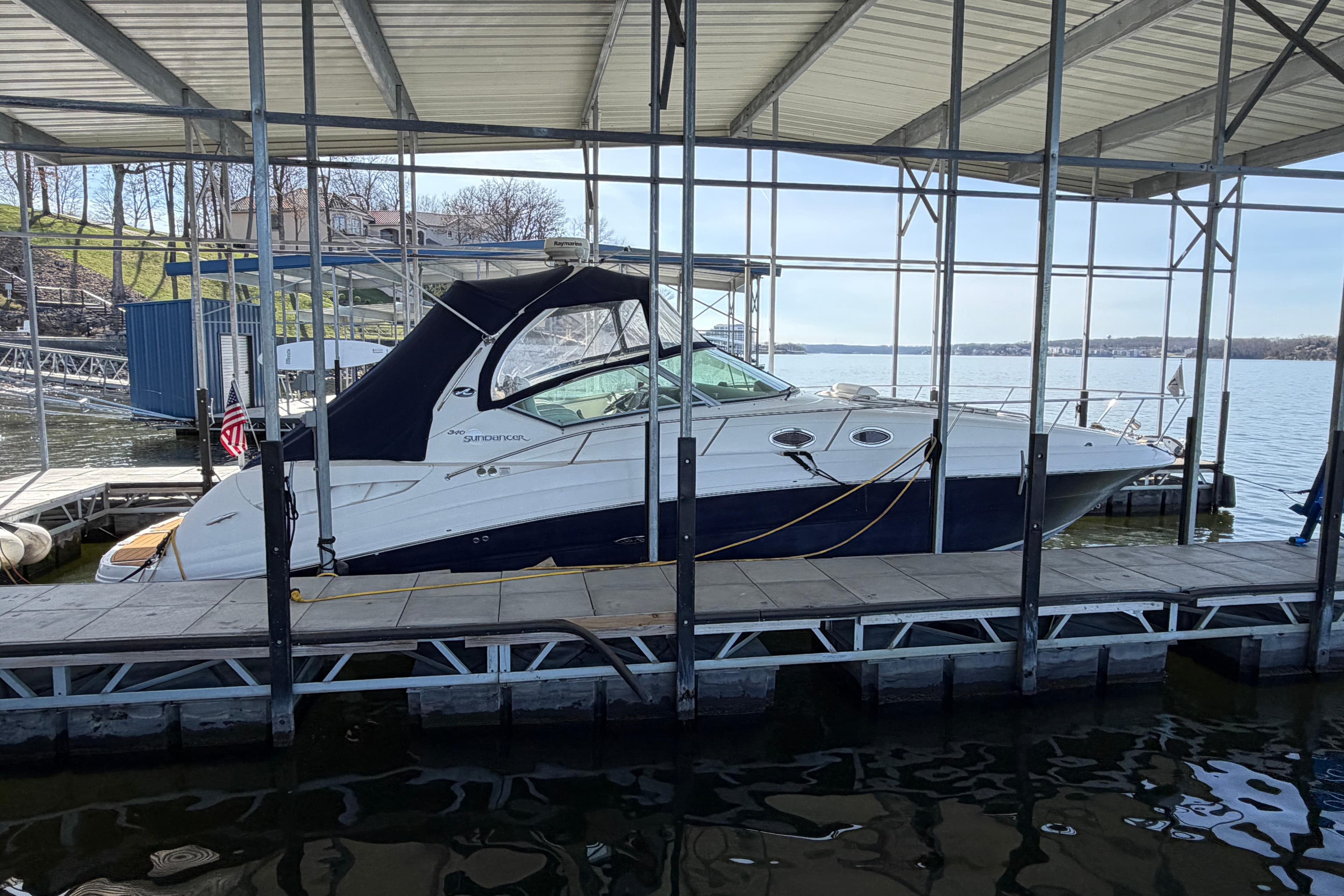 2006 Sea Ray 340 Sundancer docked under a covered marina on a sunny day.