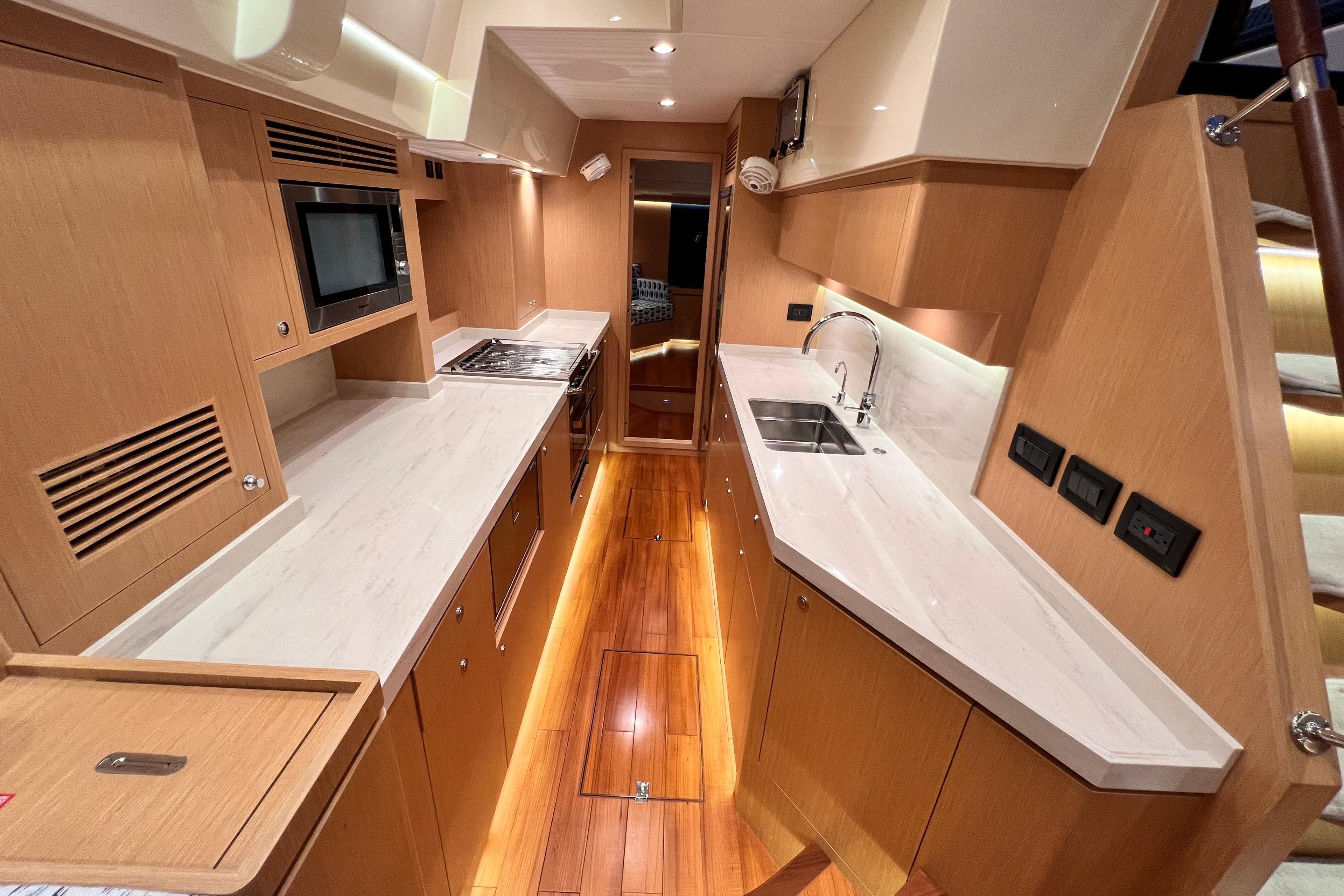 Luxurious 2024 Hylas H57 yacht kitchen with modern appliances and sleek wooden cabinetry.