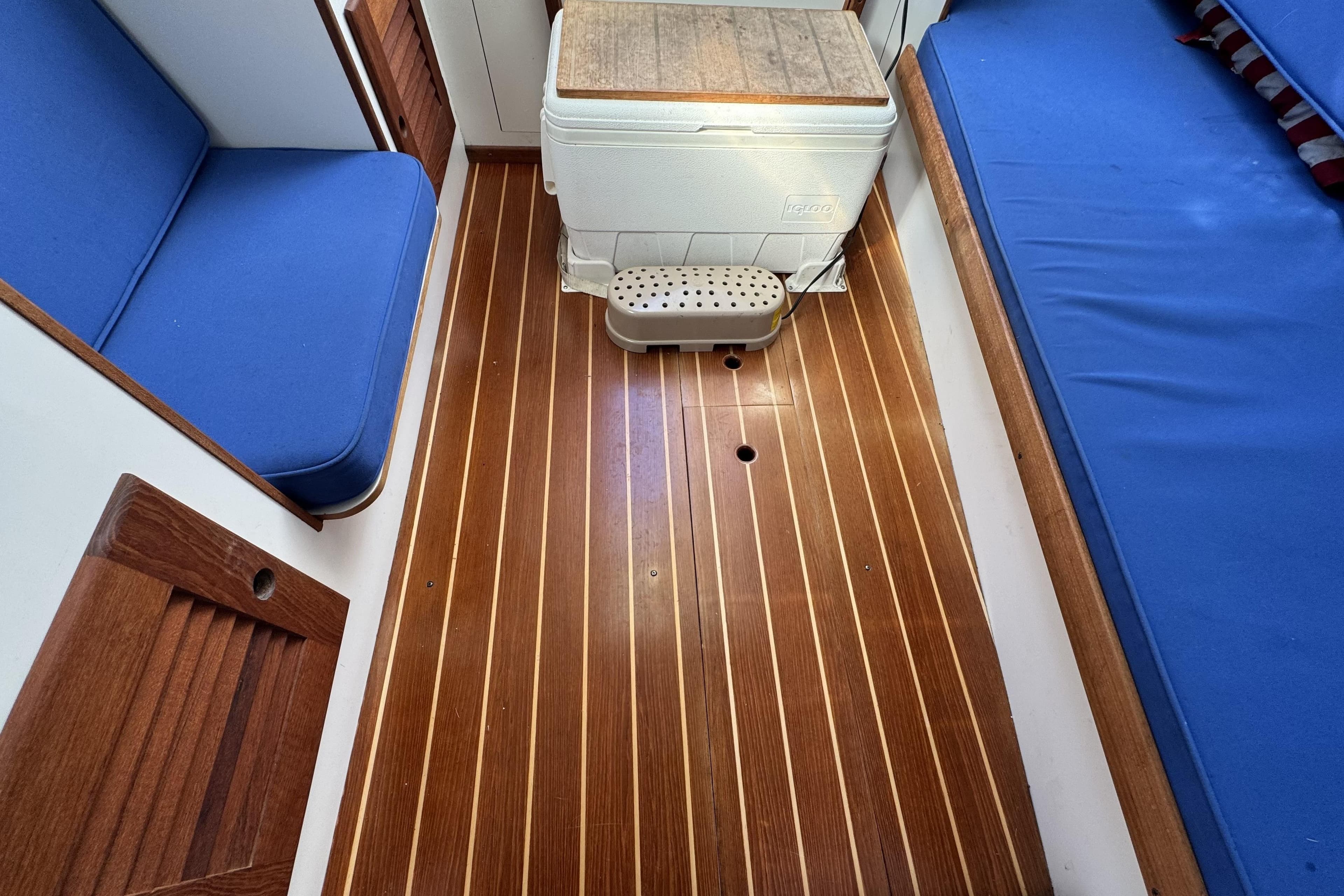 Interior of 2017 Alerion Express 28 sailboat with wooden flooring and blue seating.