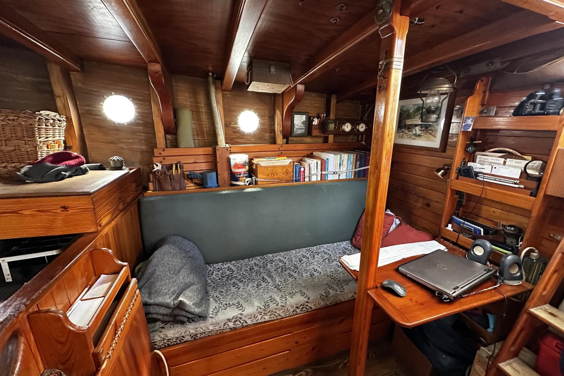 Cozy cabin interior of 2005 Custom Sail-Assisted Trawler with wooden furnishings and bookshelves.