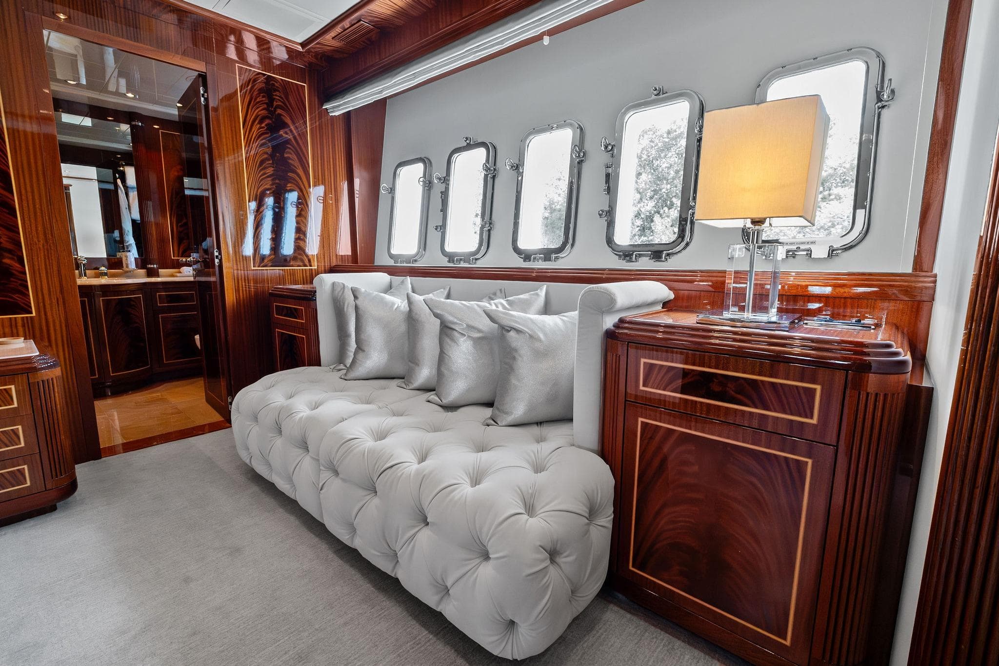 Luxurious interior of 2005 Mangusta 130 yacht with elegant wood paneling and plush seating.