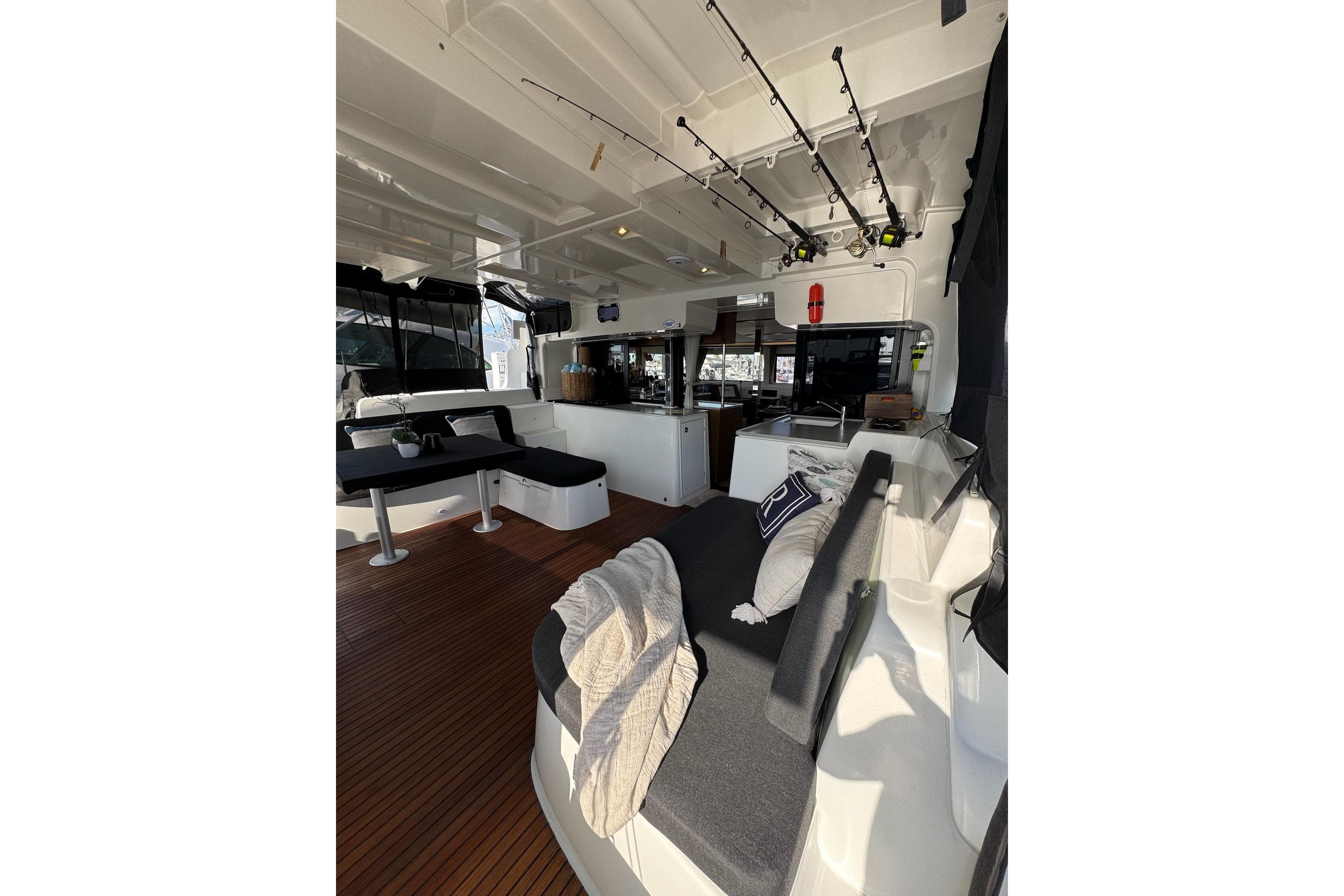 Interior of 2020 Lagoon 46 catamaran with seating, fishing rods, and wooden flooring.