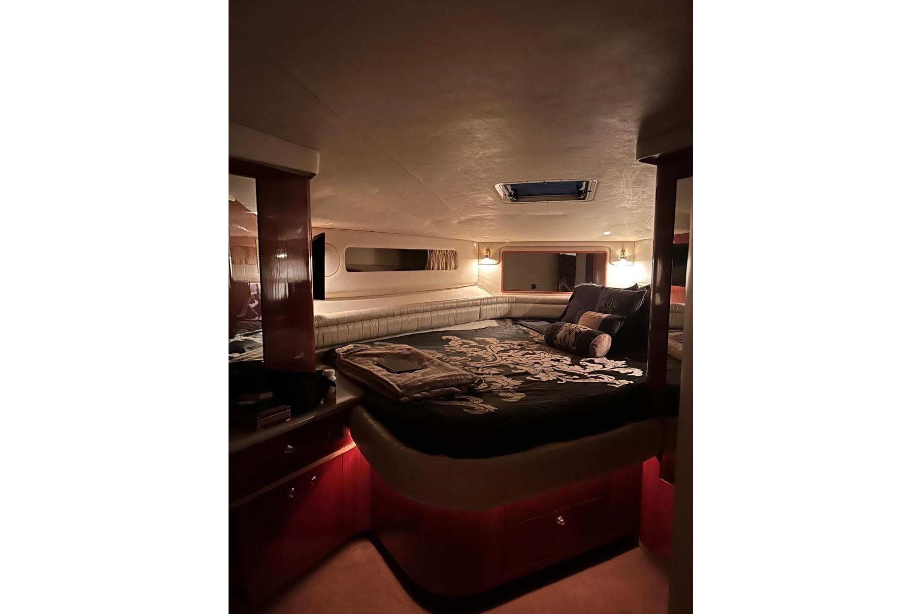 Luxurious cabin interior of 1997 Sea Ray 500 Sundancer yacht, featuring elegant bedding and ambient lighting.