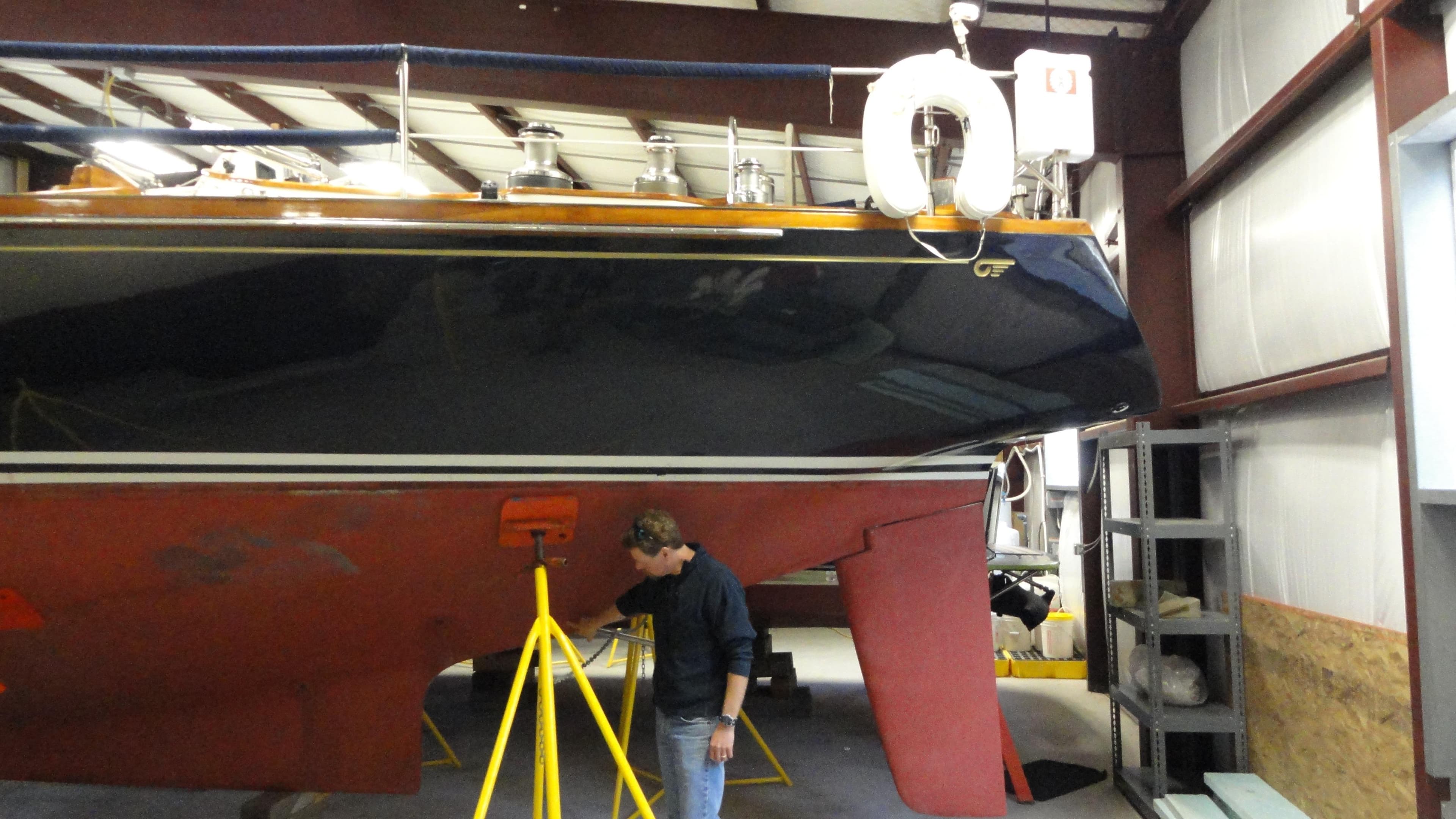 1980 Hinckley 43 sailboat in a workshop, with a person inspecting the hull.