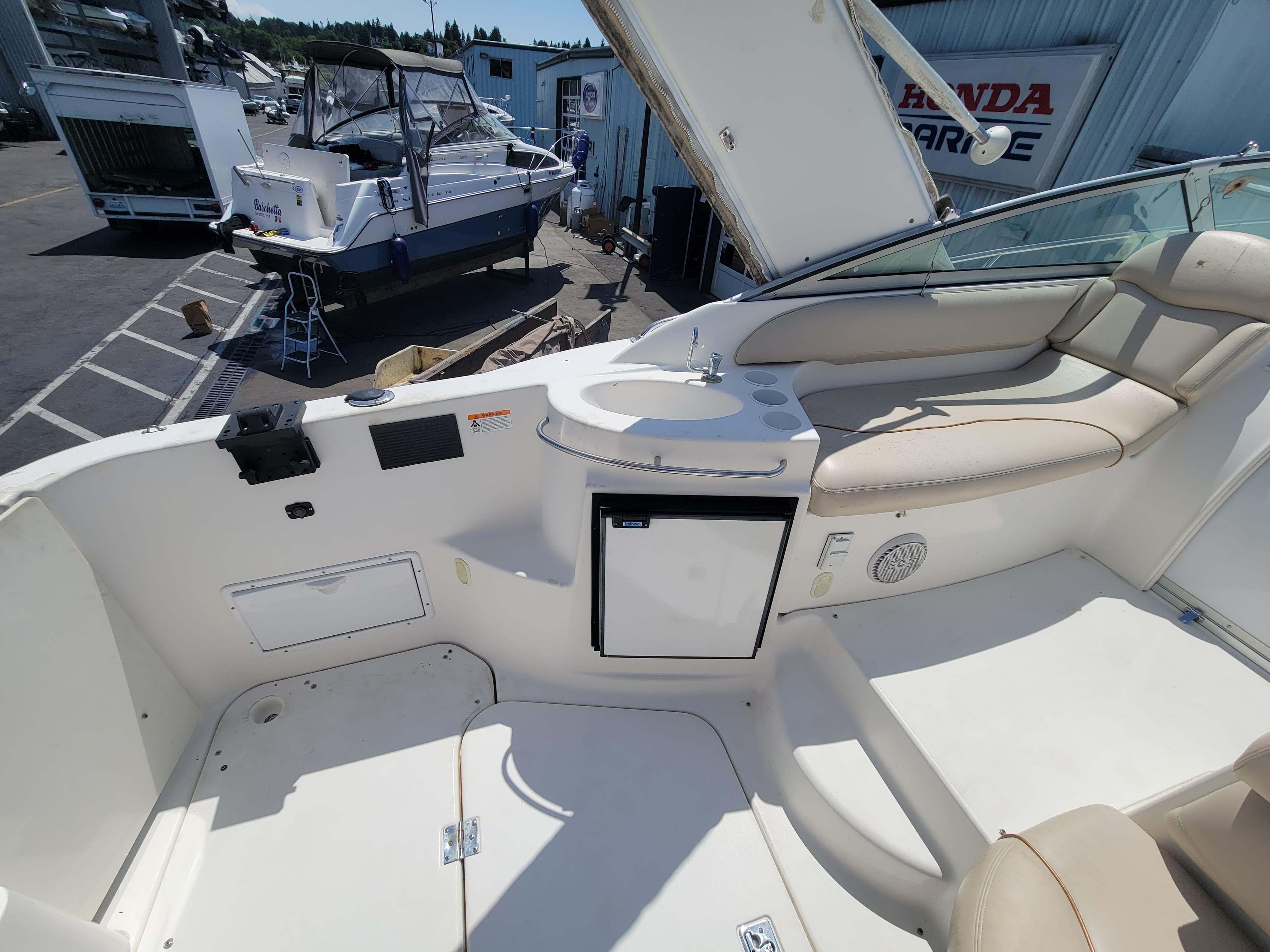 2003 Larson 310 boat interior with seating and mini fridge.