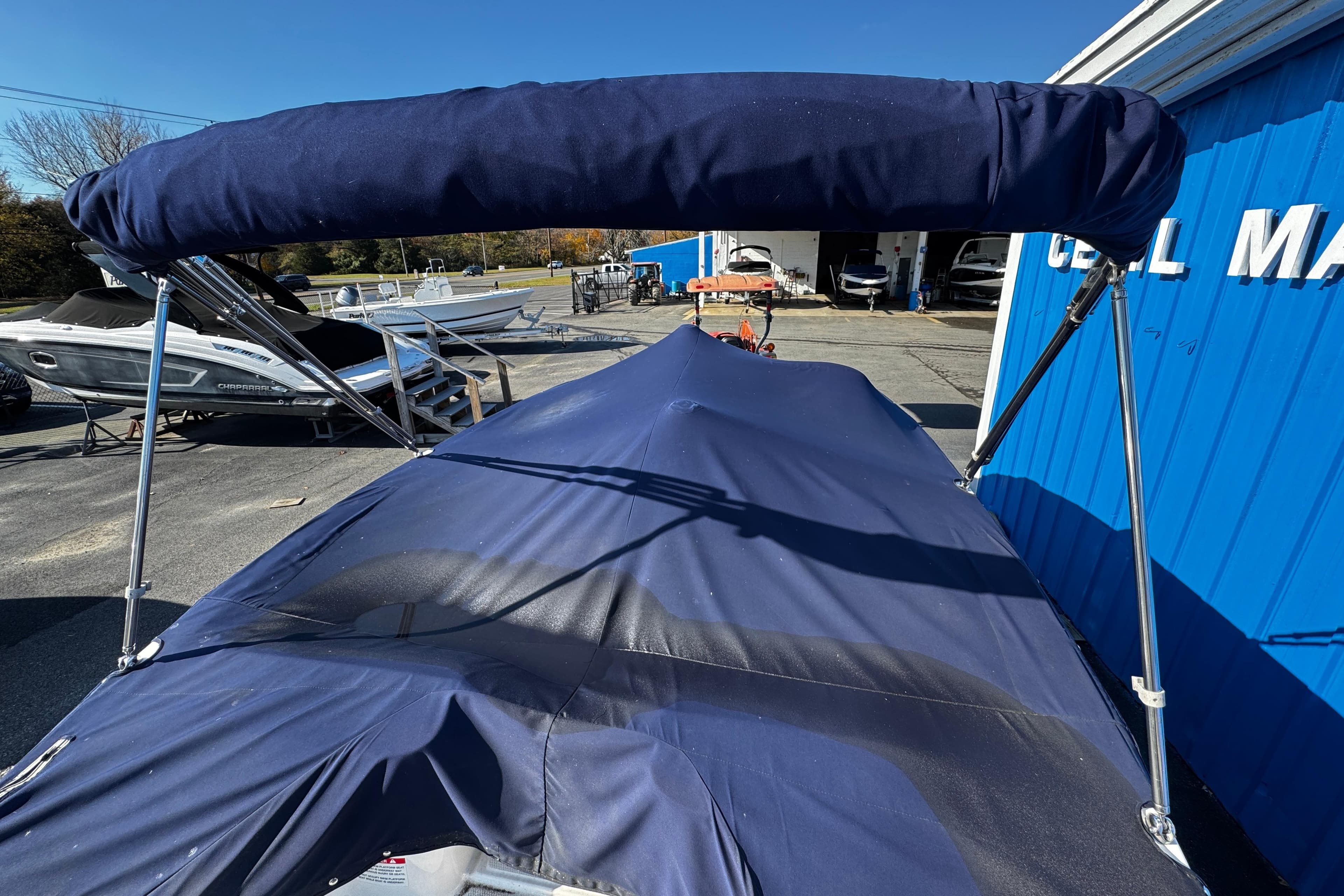 2019 Chaparral 191 Suncoast boat with blue cover and canopy in marina setting.