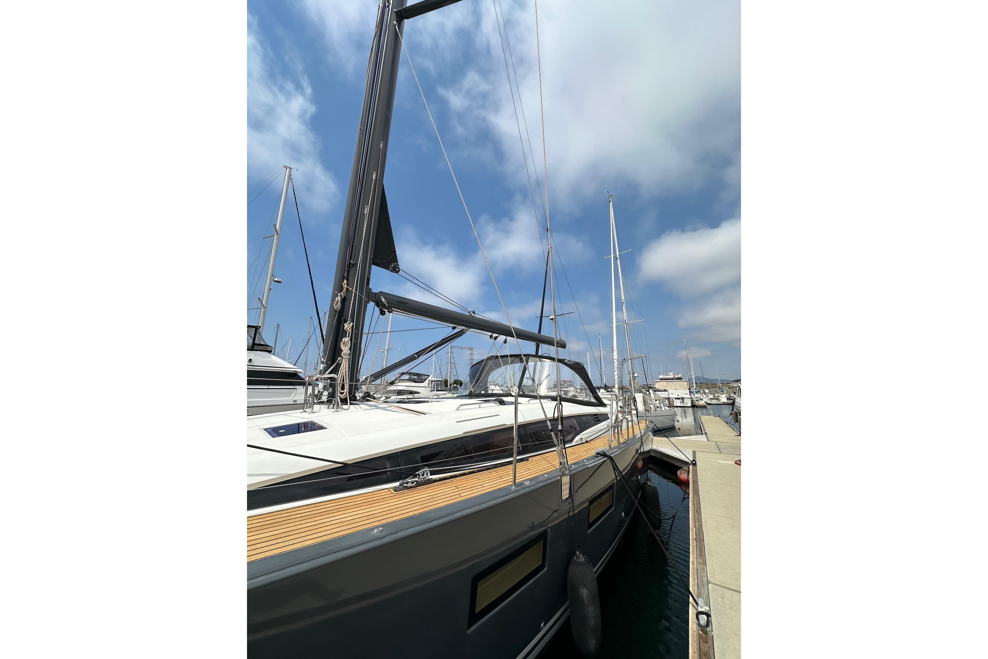 2018 Jeanneau 54 yacht docked at marina under blue sky.