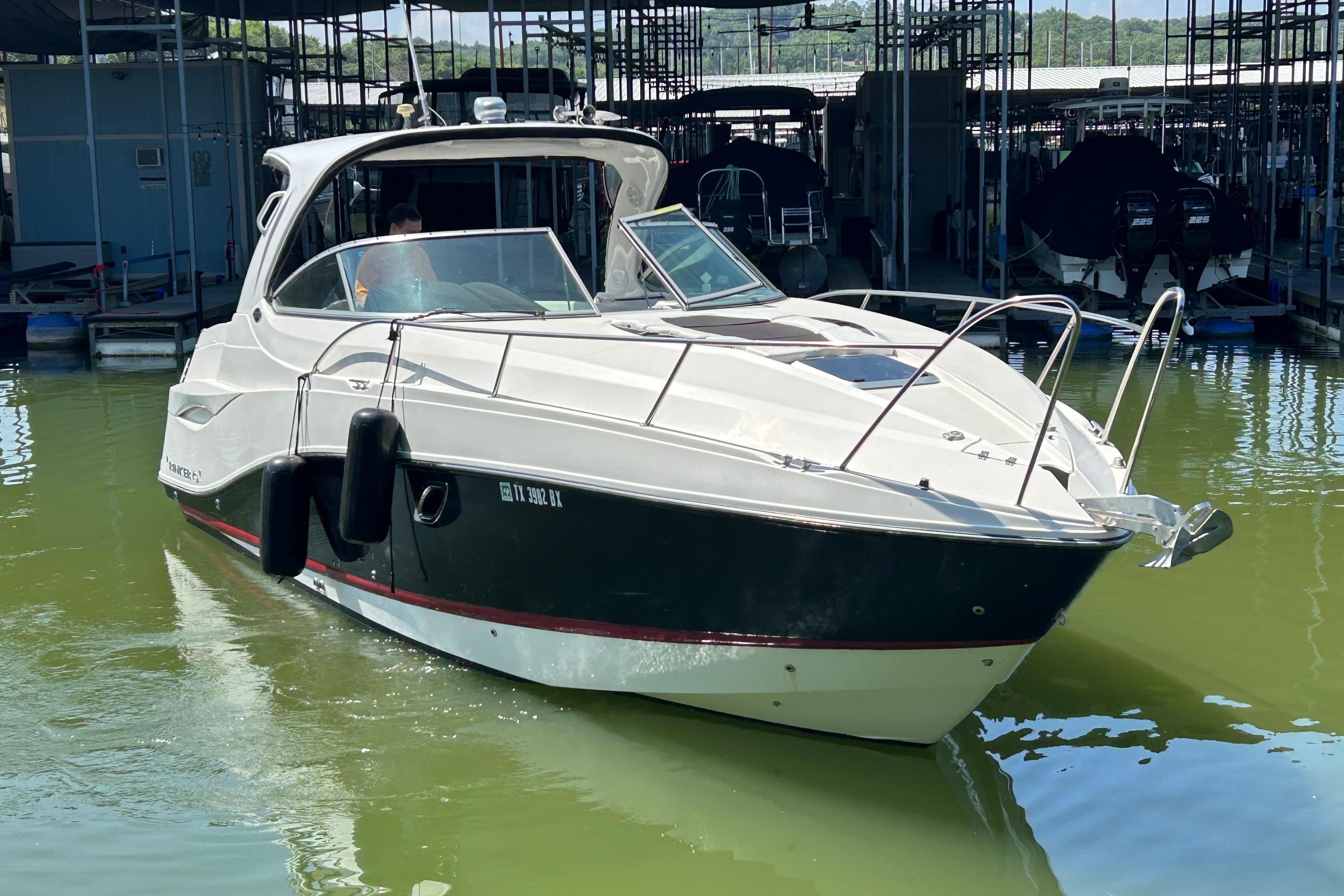 2013 Rinker 310 Express Cruiser docked in a marina, featuring sleek design and modern amenities.