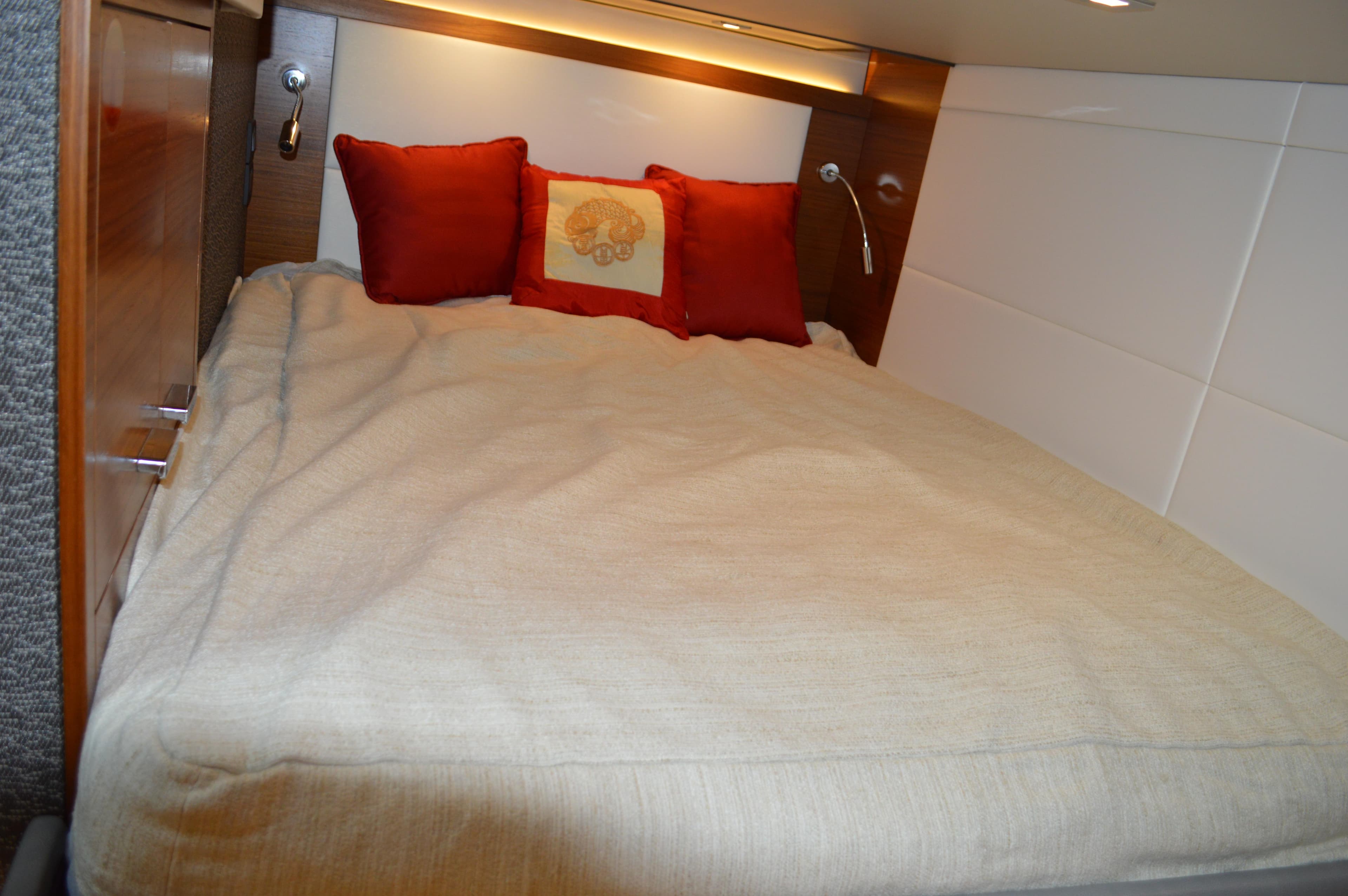 Cozy bedroom in 2019 Tiara Yachts C39 Coupe with red pillows and beige bedding.