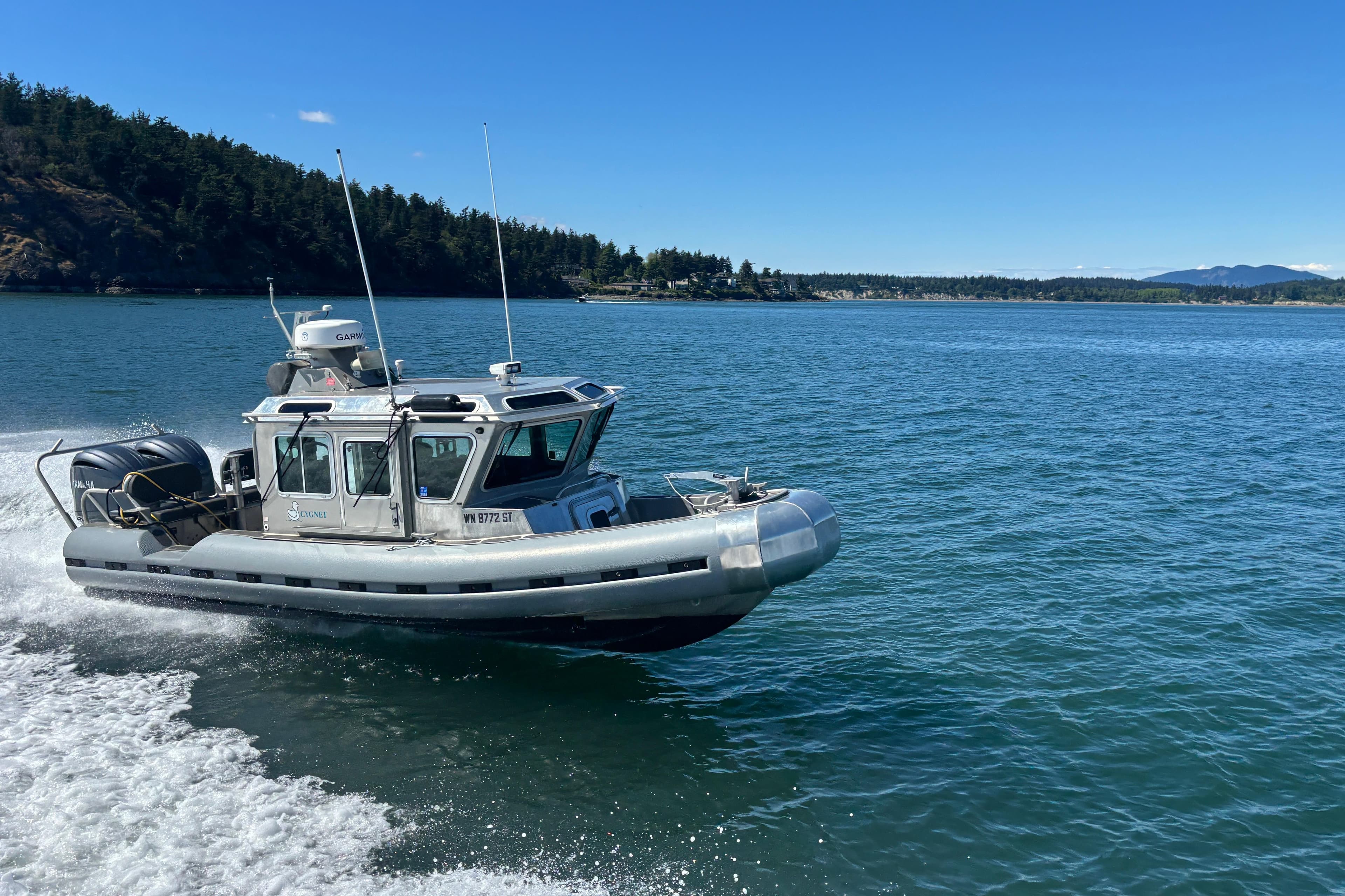 2006 SAFE Boats Defender 25 cruising on a scenic lake with forested shoreline.