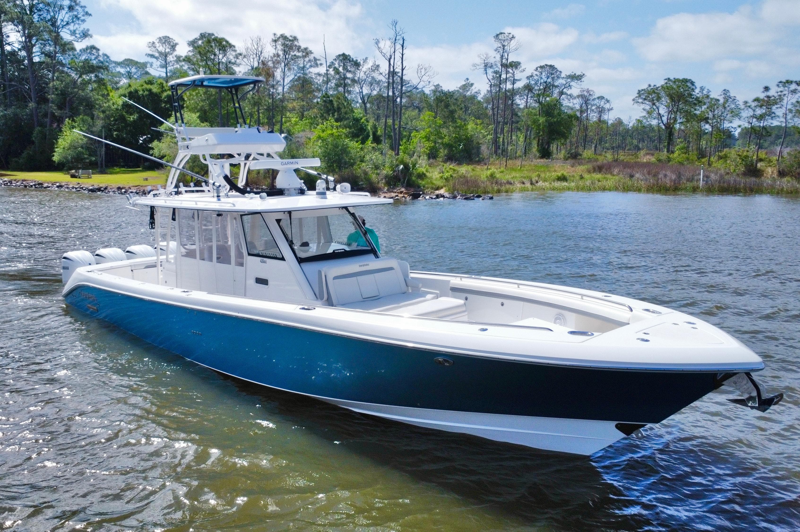 2016 Everglades 435 Center Console boat on a serene lake with lush greenery.