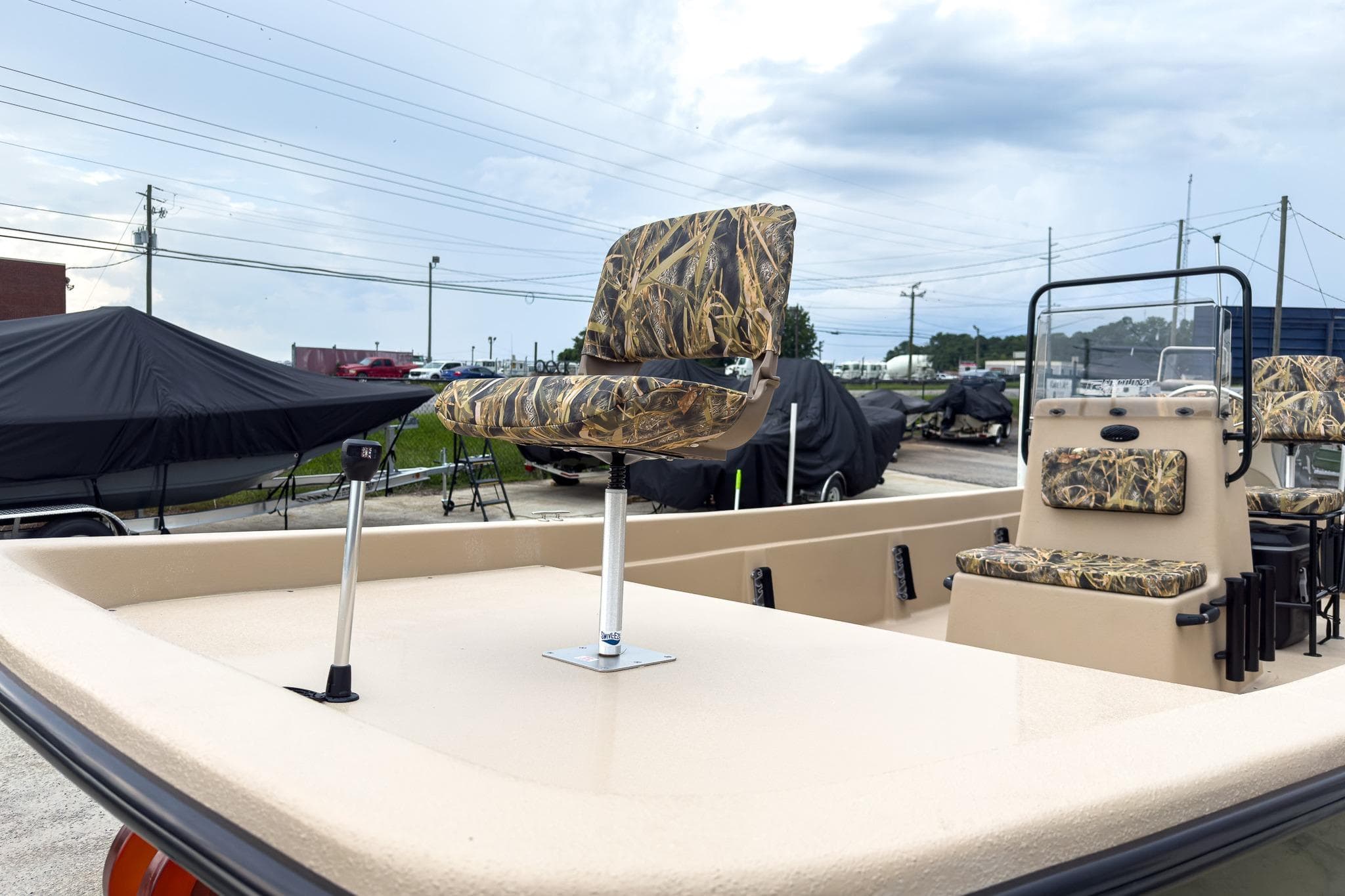 2026 Carolina Skiff E21 DLX CC boat with camo seats, parked outdoors.