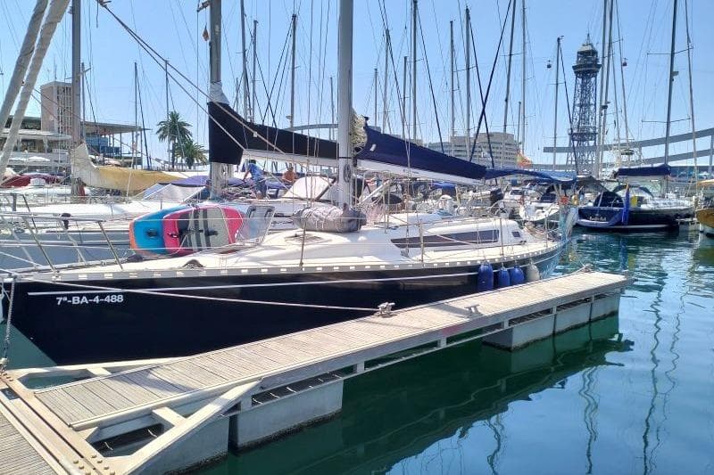 Sailboat docked in marina, Omega custom model, 1988, with vibrant surroundings.