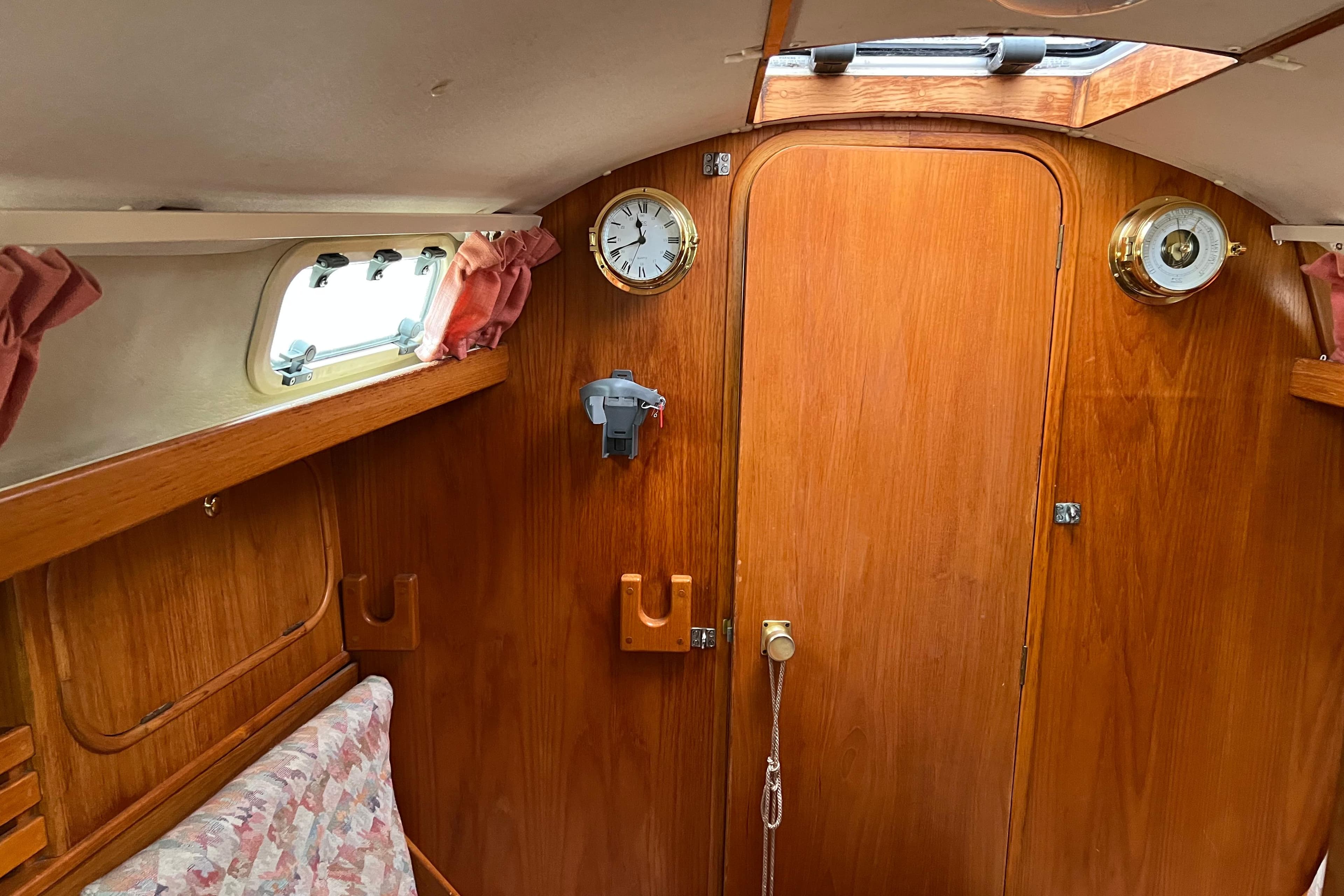 Interior of Vancouver 28 sailboat with wooden paneling and nautical clock.