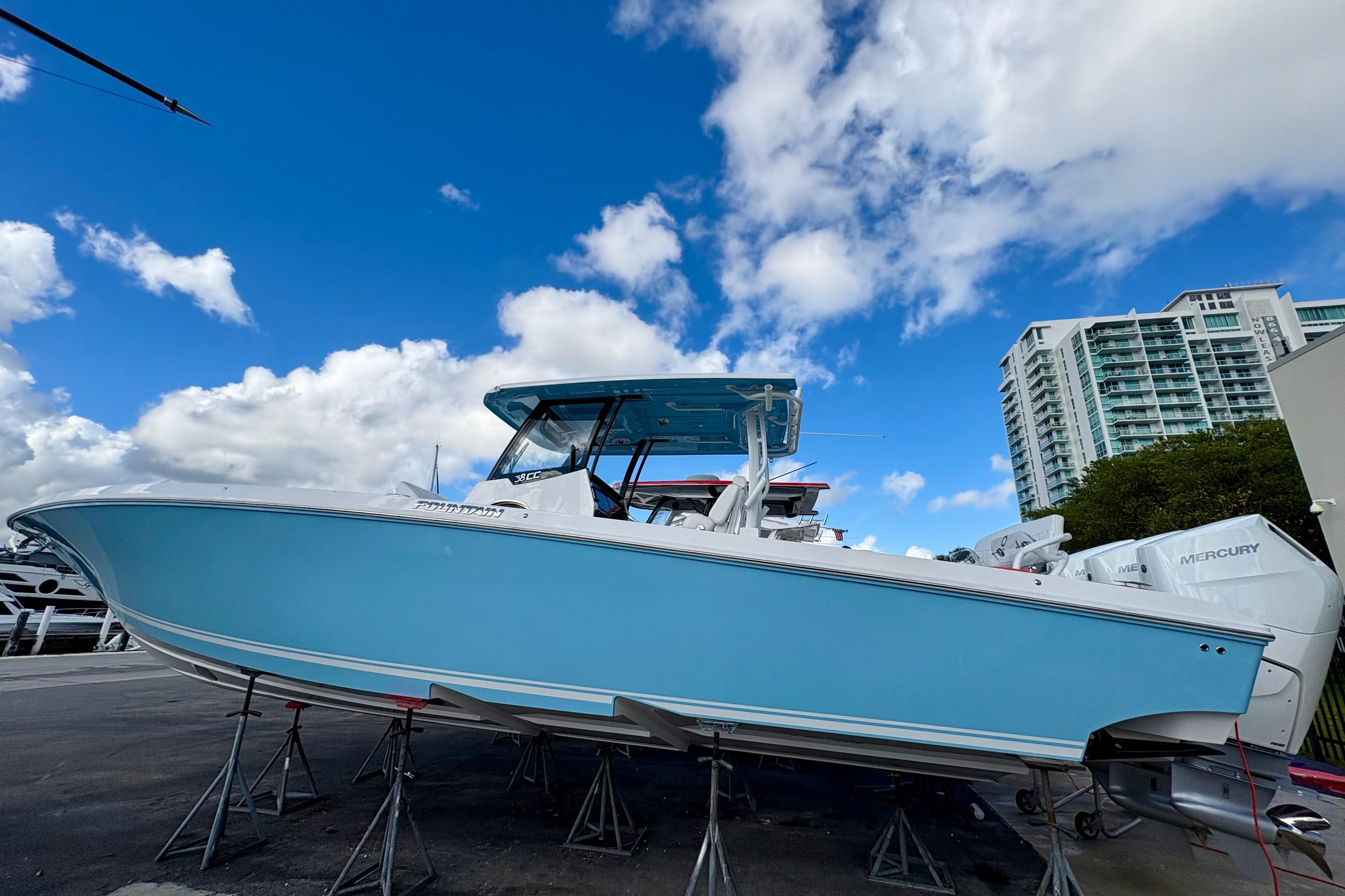 2025 Fountain 38 Center Console boat on stands, blue hull, clear sky background.