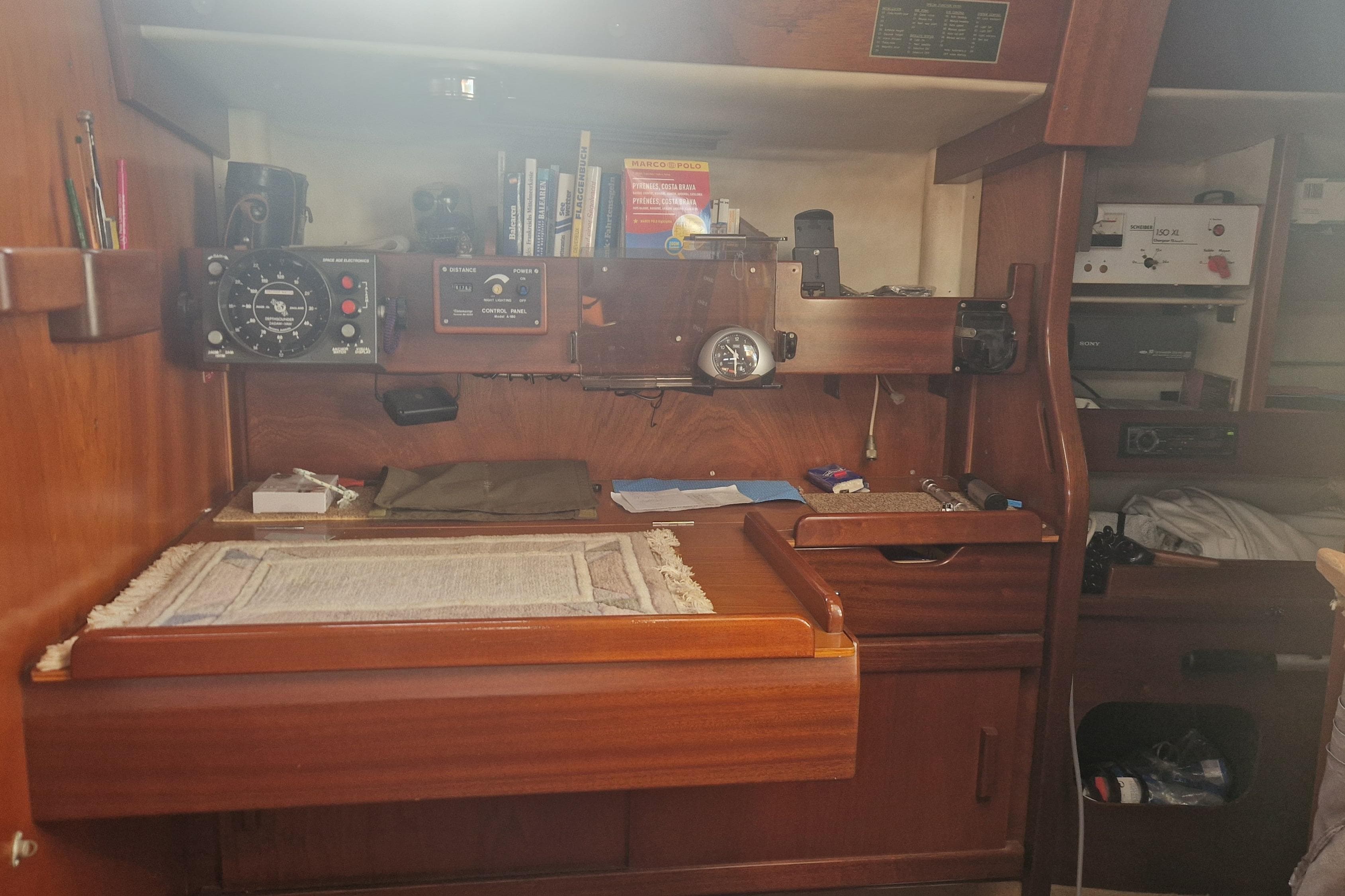 Navigation station inside a 1980 Amel Sharki sailboat, featuring instruments and charts.