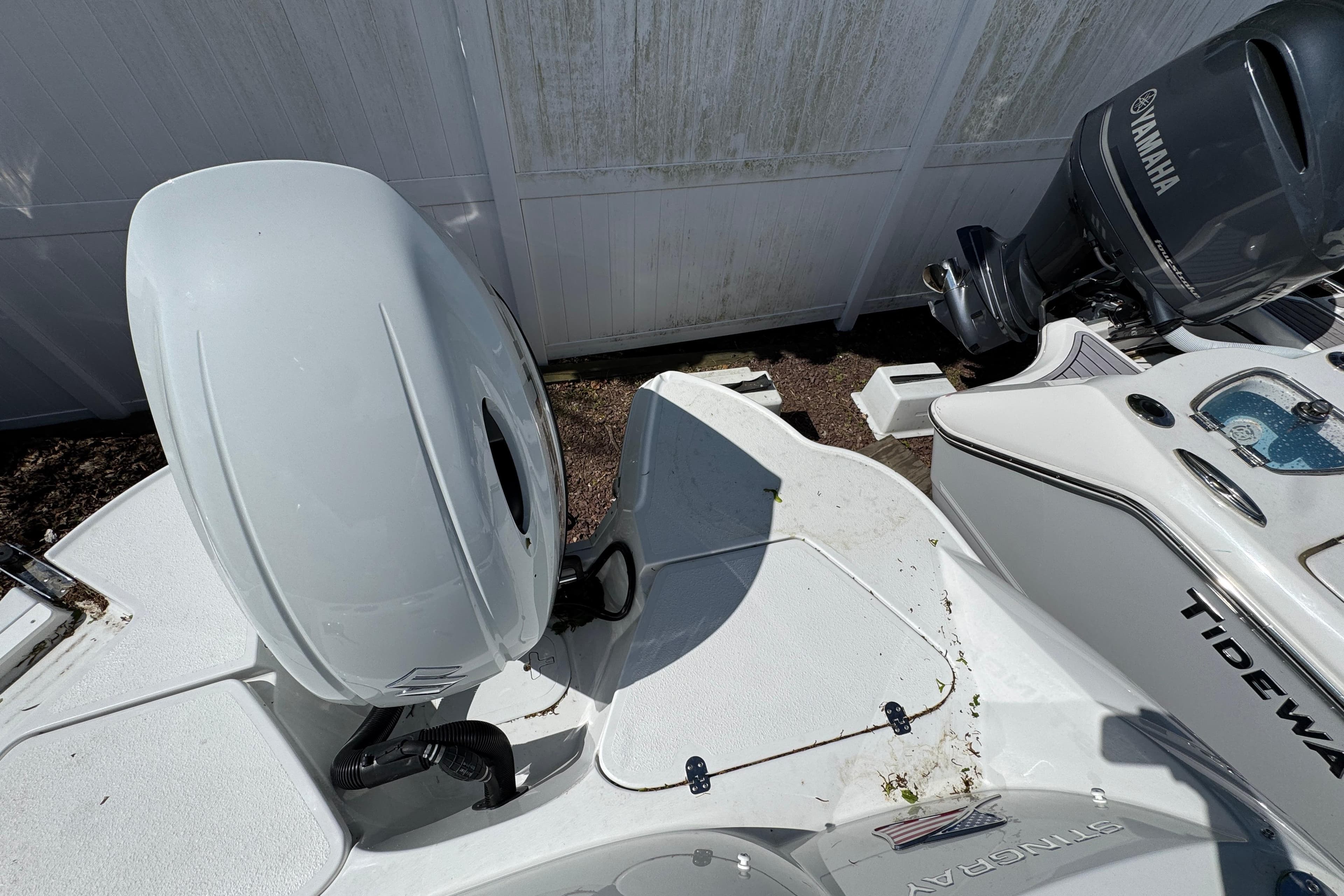 Stingray 211 DC 2026 boat with Yamaha outboard motor, parked near a white fence.