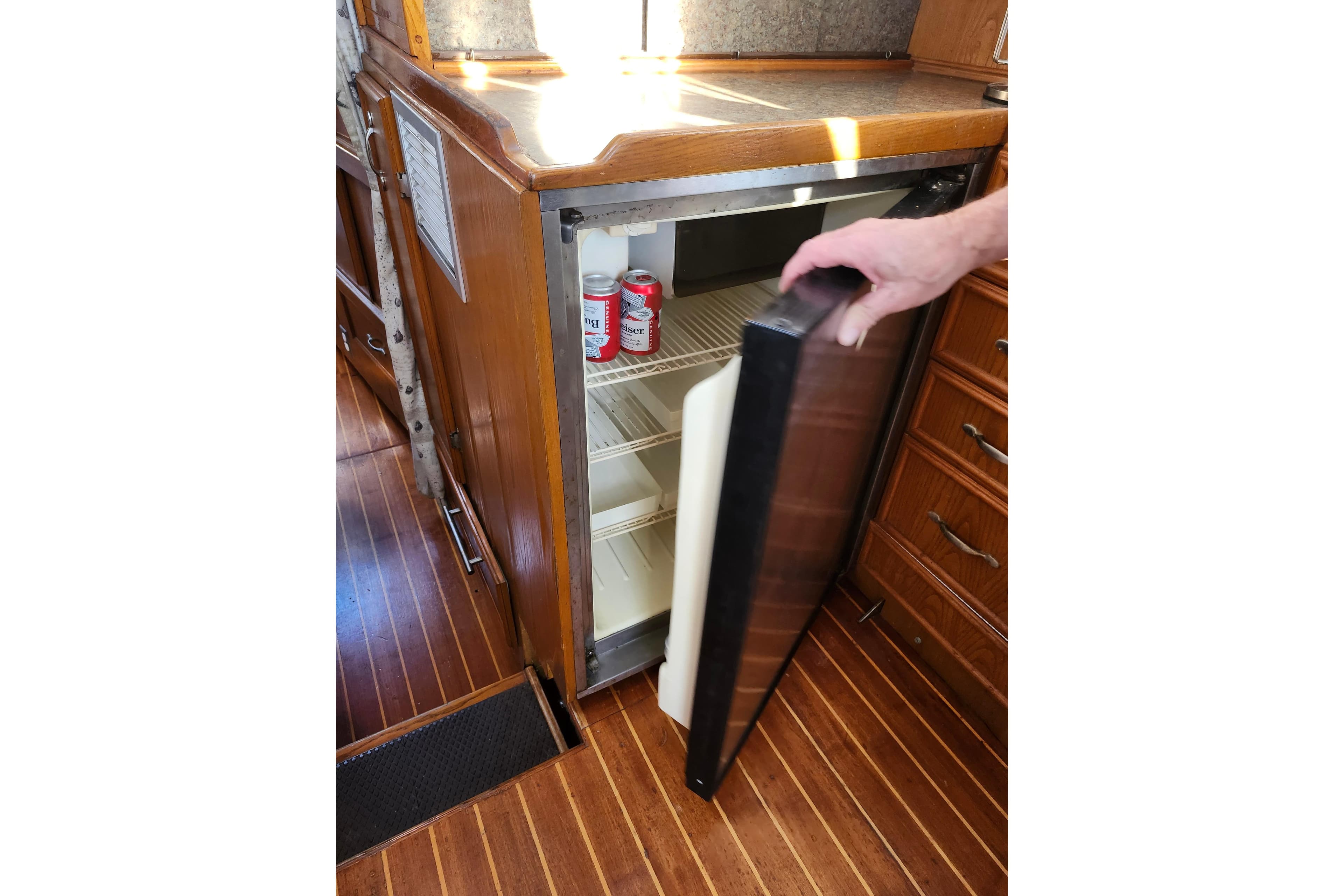 1987 Custom Weld Exploration boat interior with open fridge and wooden cabinetry.