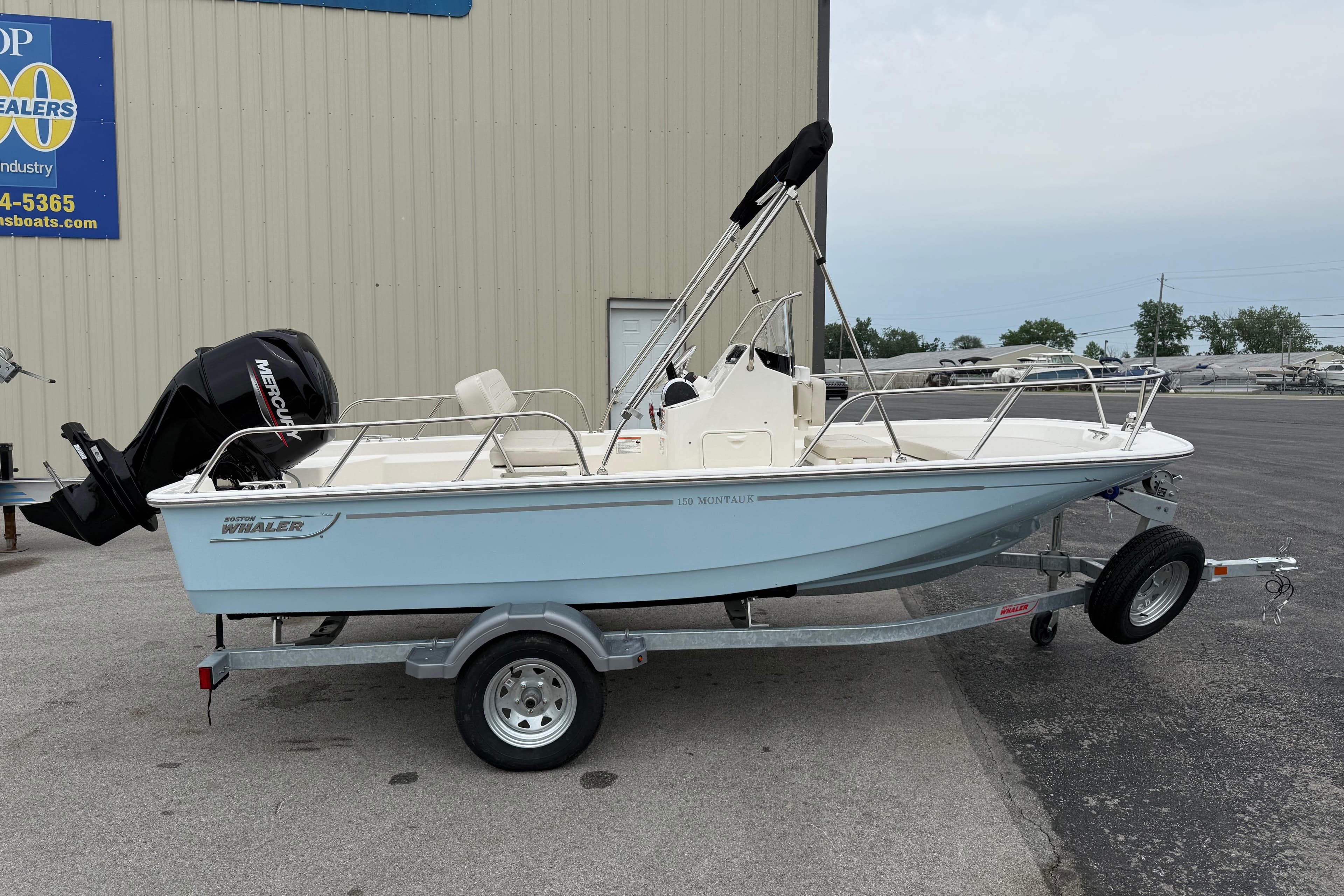 2026 Boston Whaler 150 Montauk boat on trailer, parked outside a dealership.