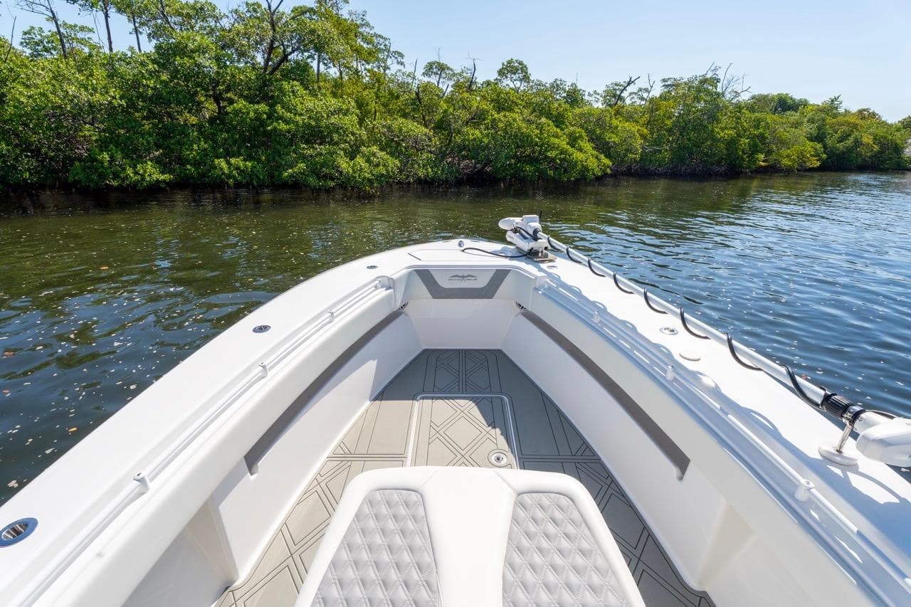 2025 Invincible 33 Open Fisherman boat on calm water near lush greenery.