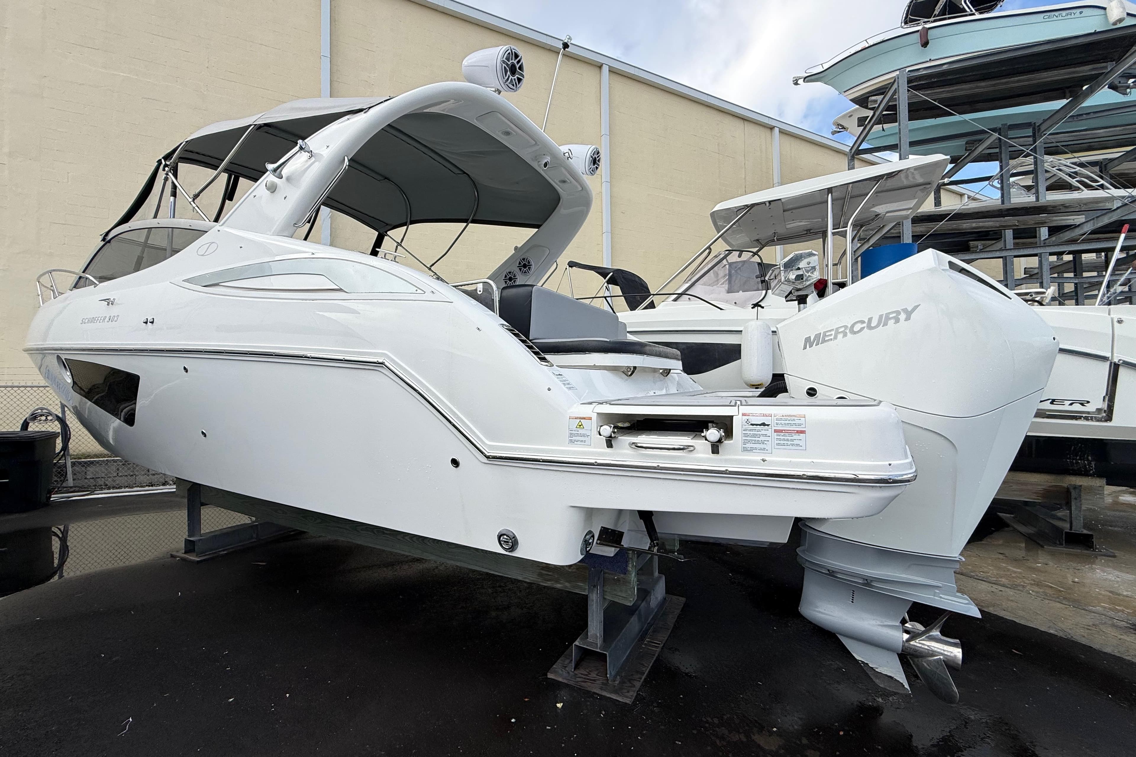 2021 Schaefer 303 boat with Mercury engine, displayed on a stand in a marina.
