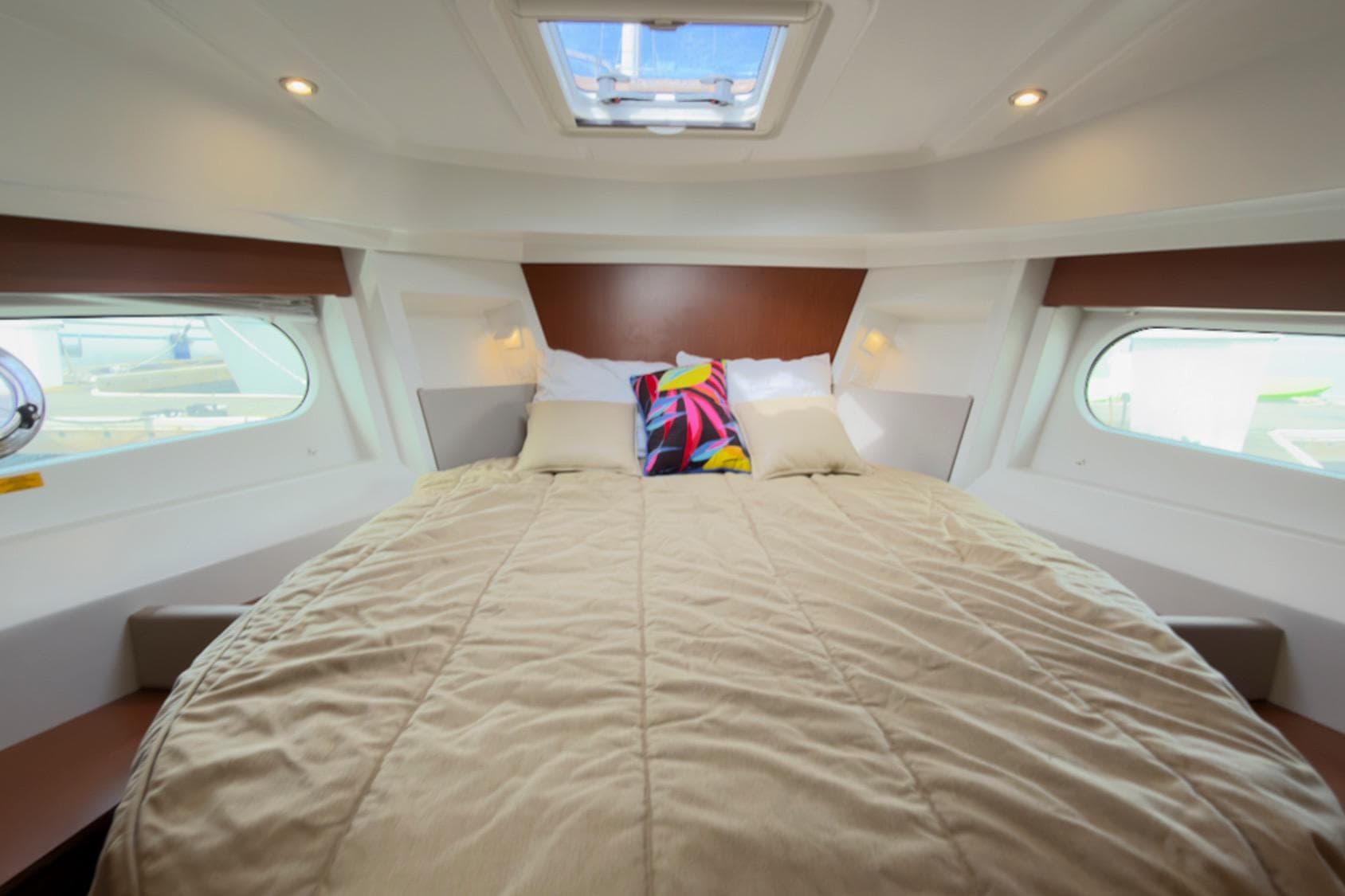 Interior cabin of 2016 Beneteau Swift Trawler 30 with cozy bed and porthole windows.