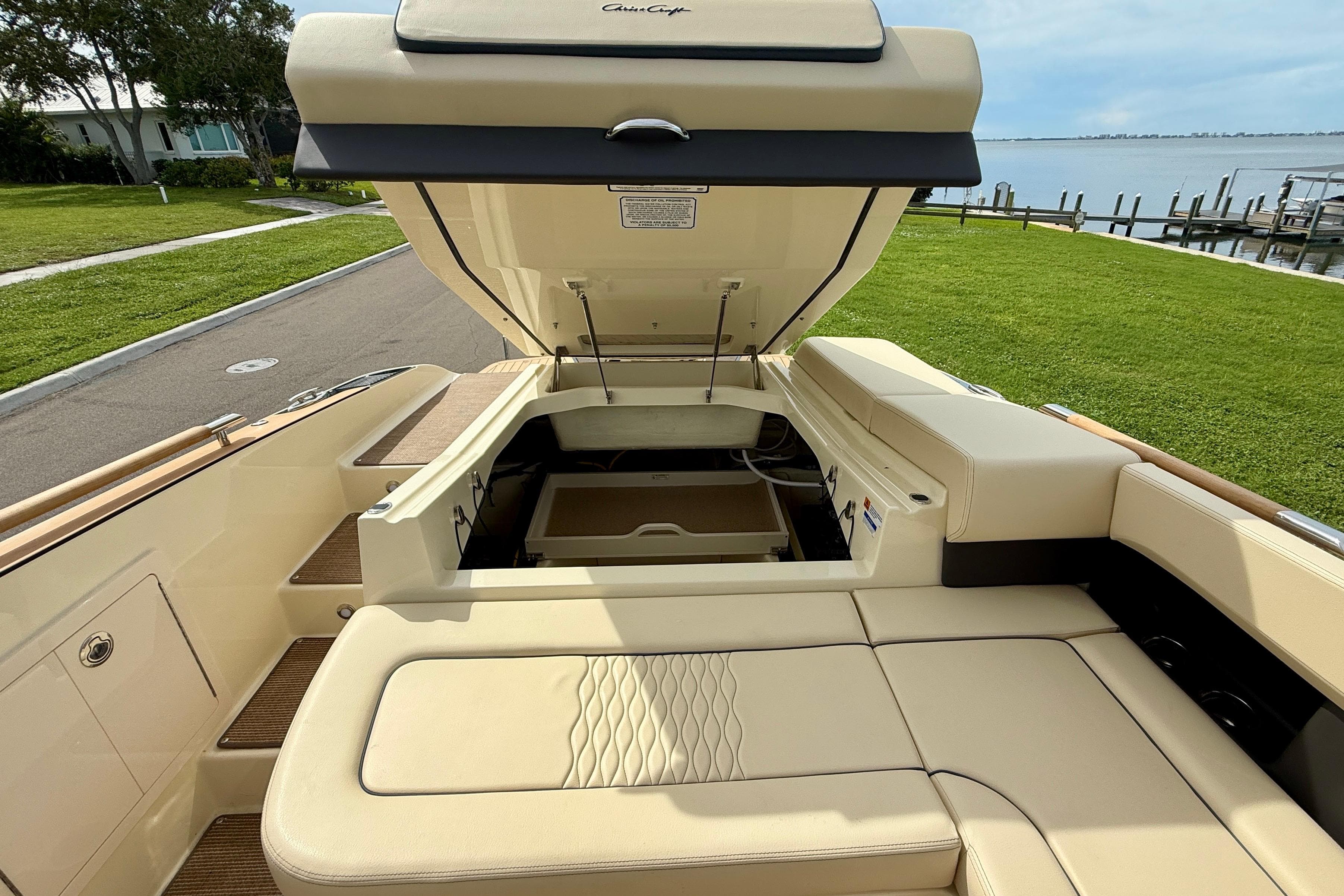 2026 Chris-Craft Sportster 28 boat interior with open engine compartment, beige seating, and waterfront view.