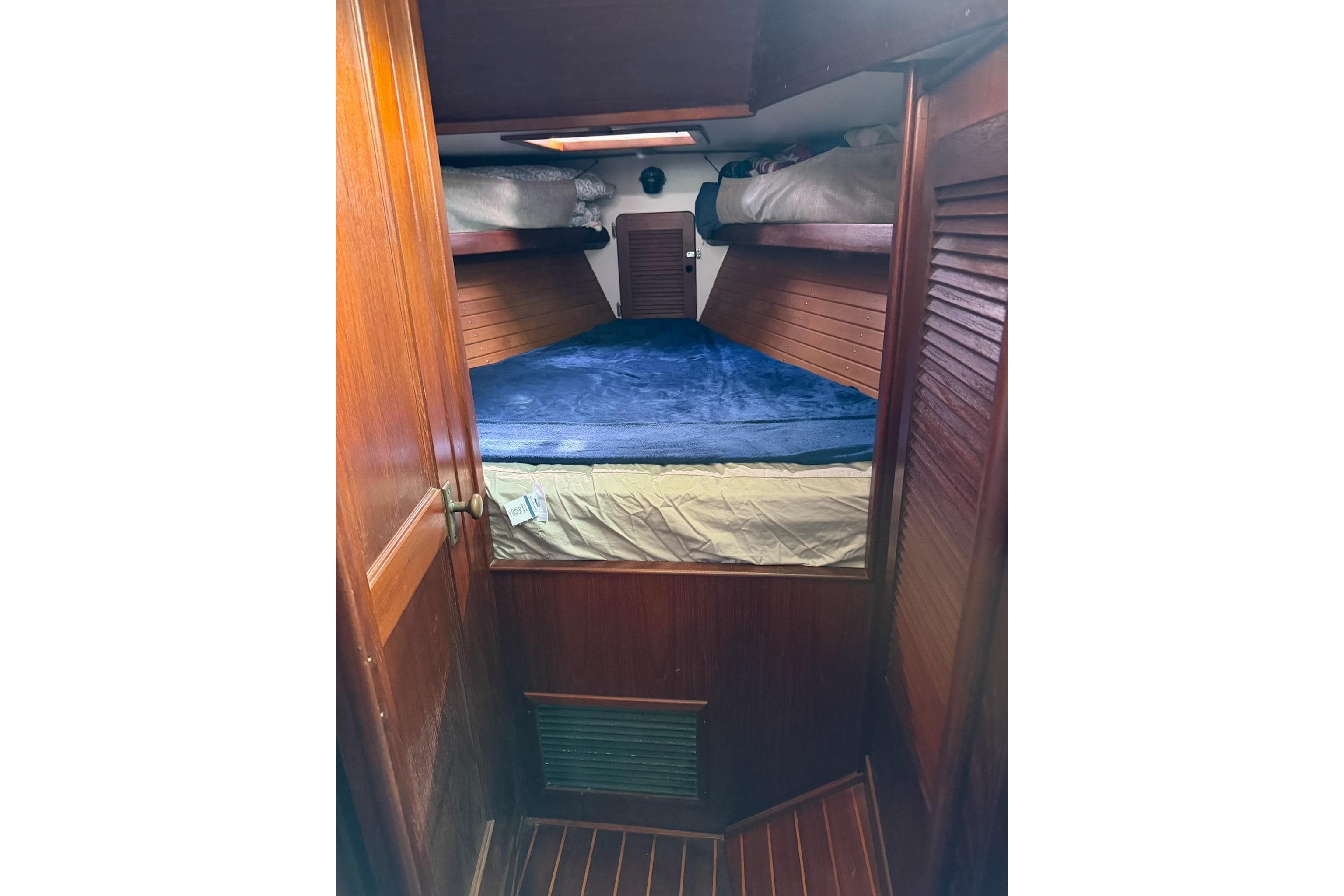 Cozy cabin interior of 1984 Morgan 384 sailboat with wooden finish and blue bedding.