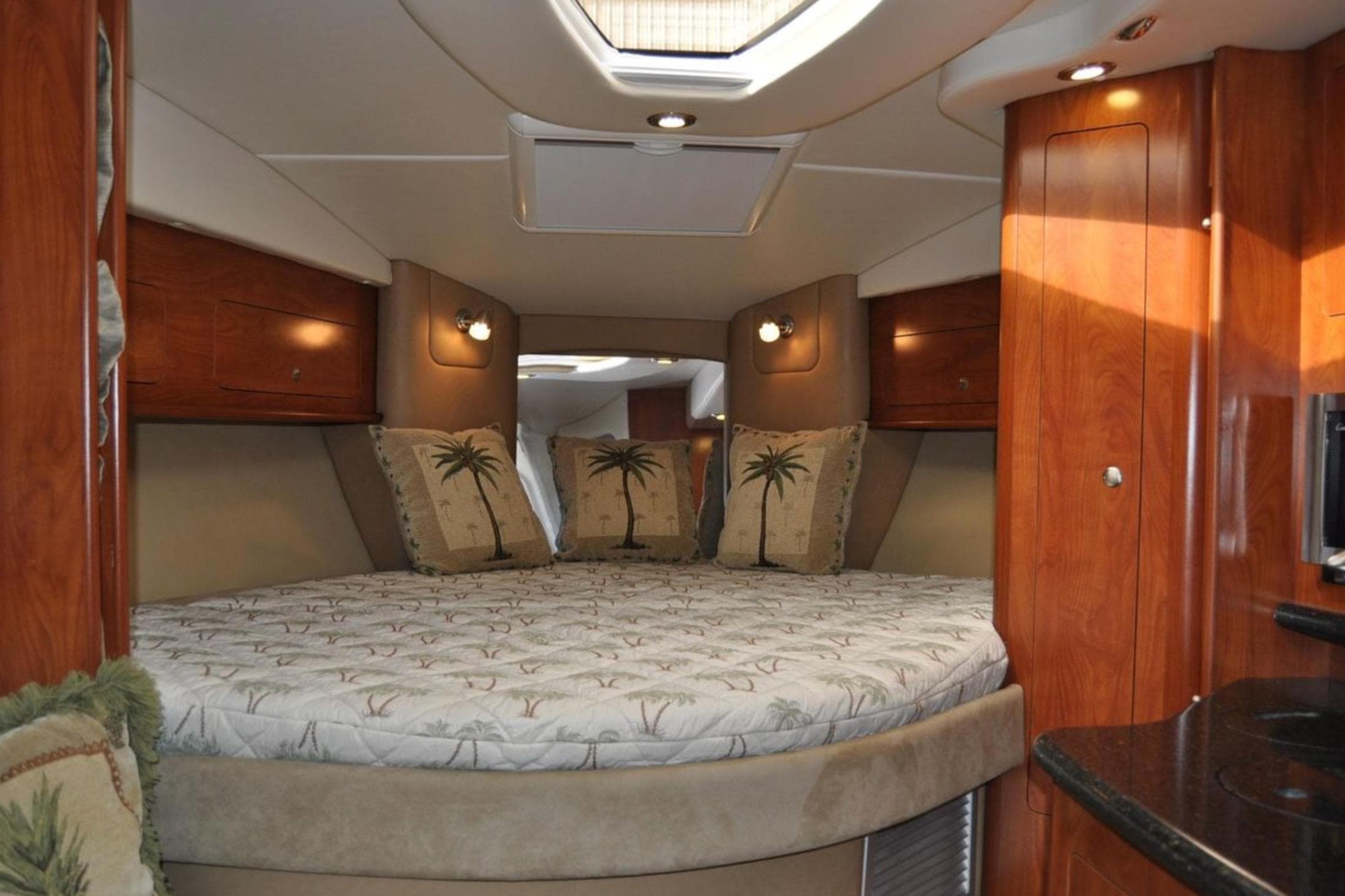 Luxurious interior of 2012 Rinker 310 Express Cruiser with cozy bed and elegant wood finish.