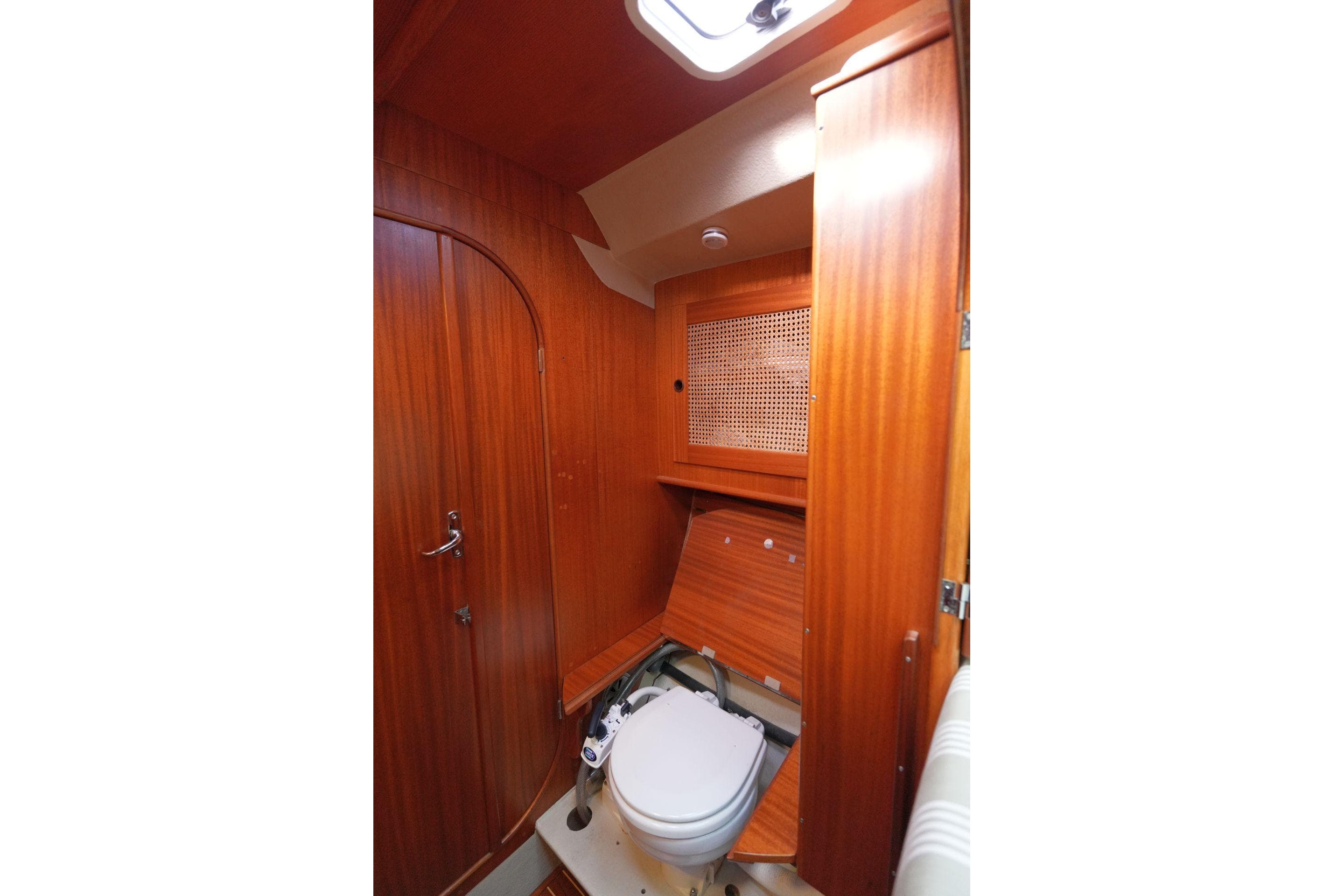 Wood-paneled bathroom in 1981 Bianca 414 yacht, featuring compact toilet and storage.
