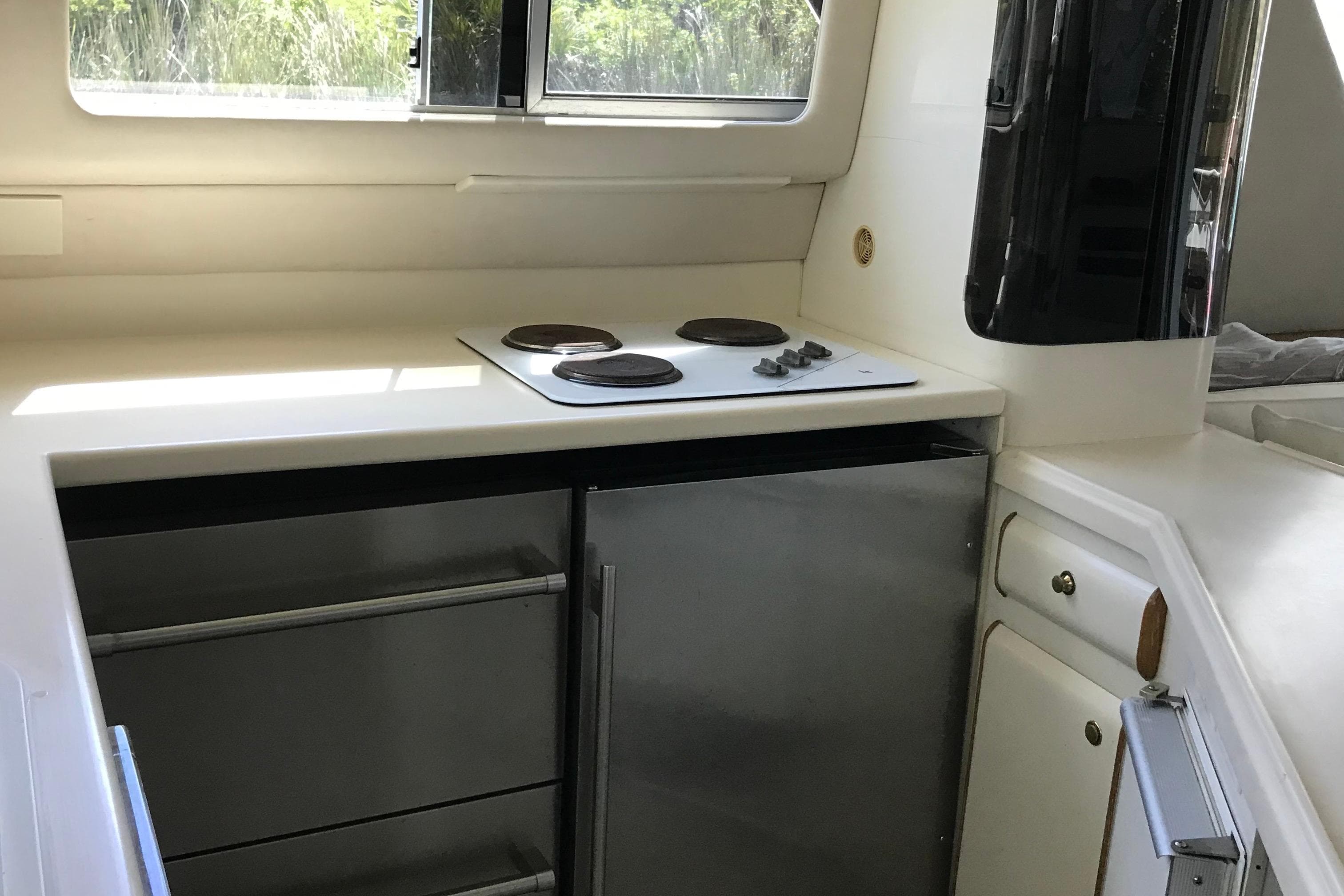 Compact kitchen area in a 1995 Sea Ray 550 Sedan Bridge yacht, featuring a stovetop and storage.