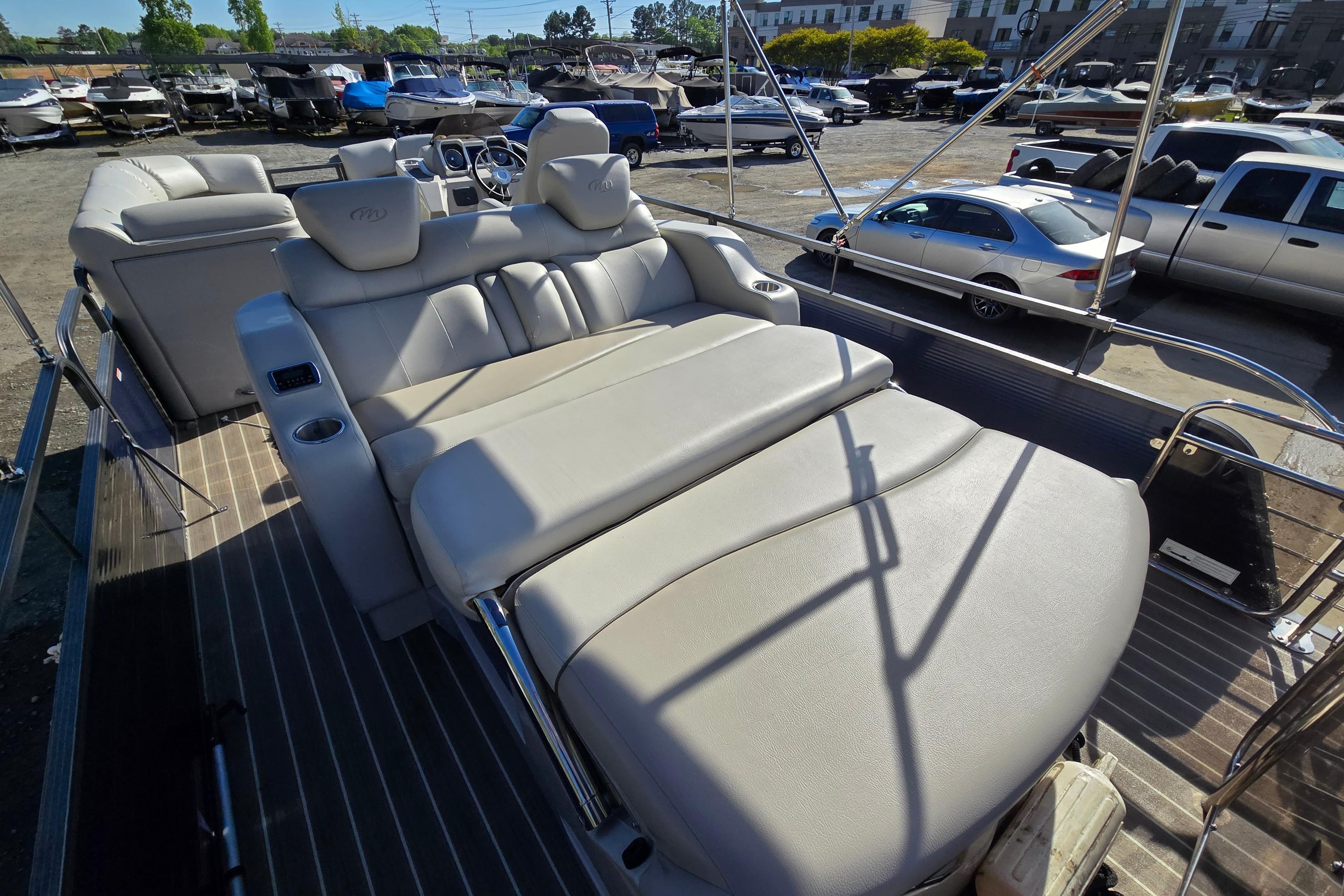 2015 Manitou 25 SES boat with luxurious seating and sleek design in a marina setting.