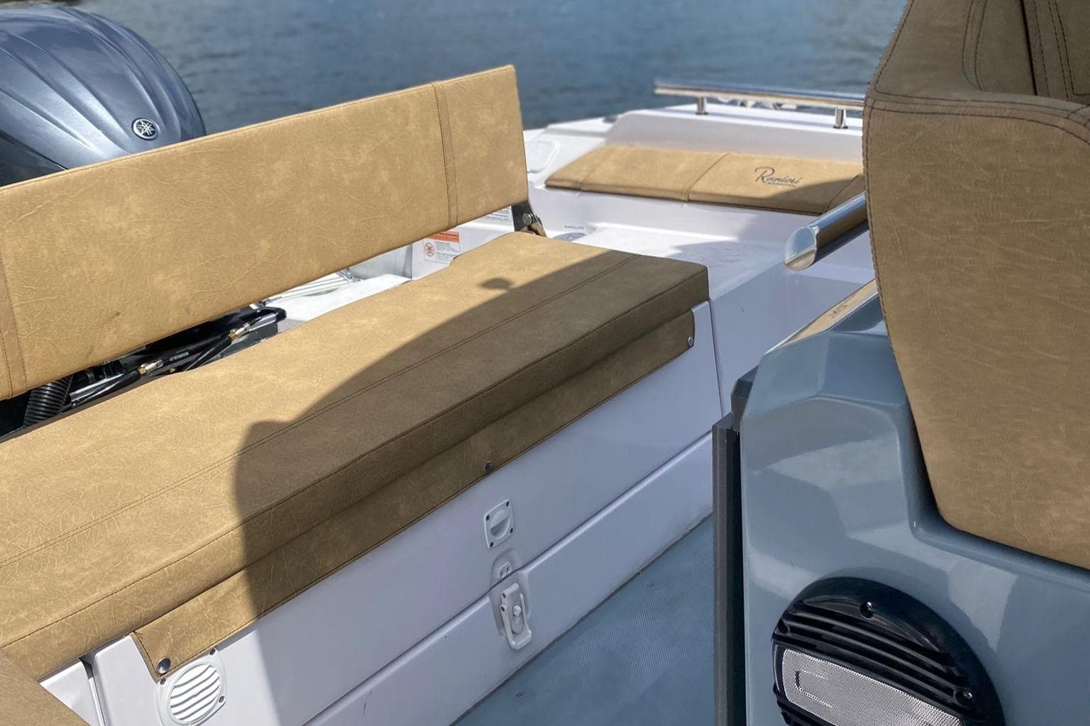 2025 Ranieri Cayman 23.0 Sport Touring boat interior with tan seating and water backdrop.