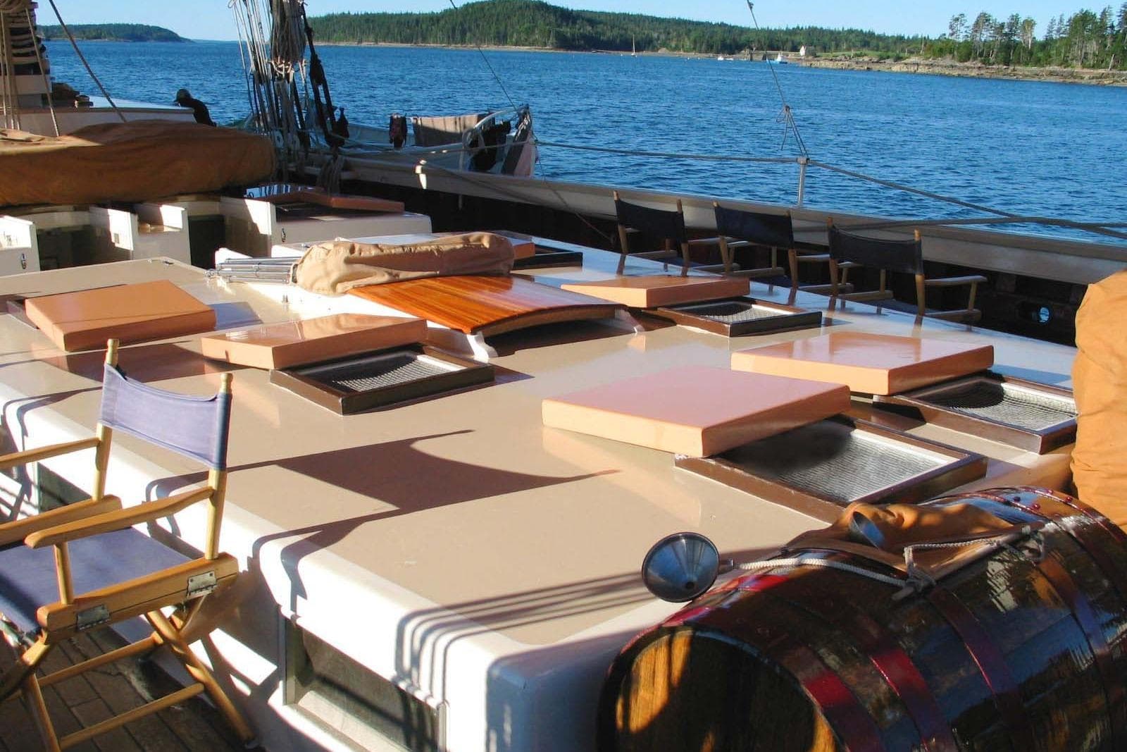 Classic 1962 Coasting Schooner deck with chairs, hatches, and scenic ocean view.