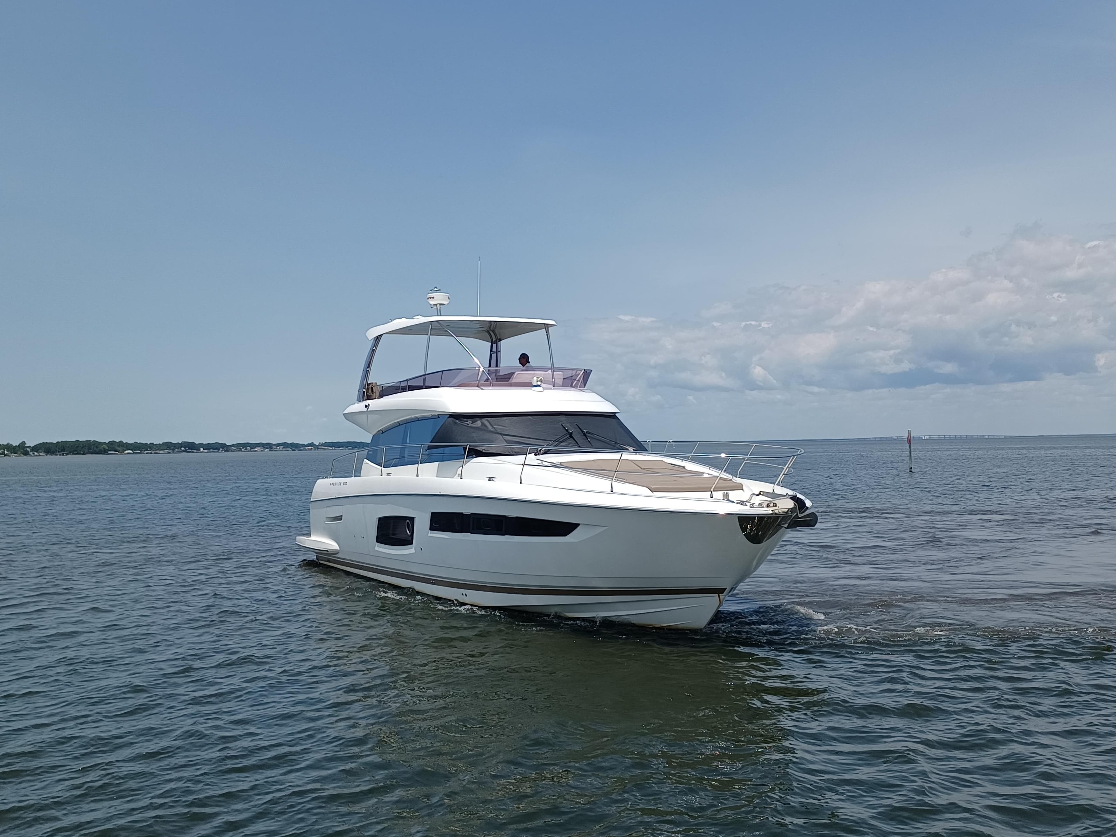2015 Prestige 550 Flybridge yacht cruising on open water under a clear sky.