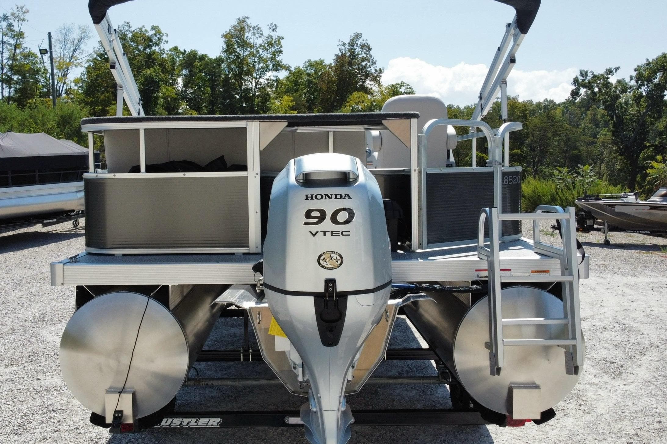 2025 Montego Bay 90HP C8520 STD Cruise Pontoon with Honda engine, parked outdoors.
