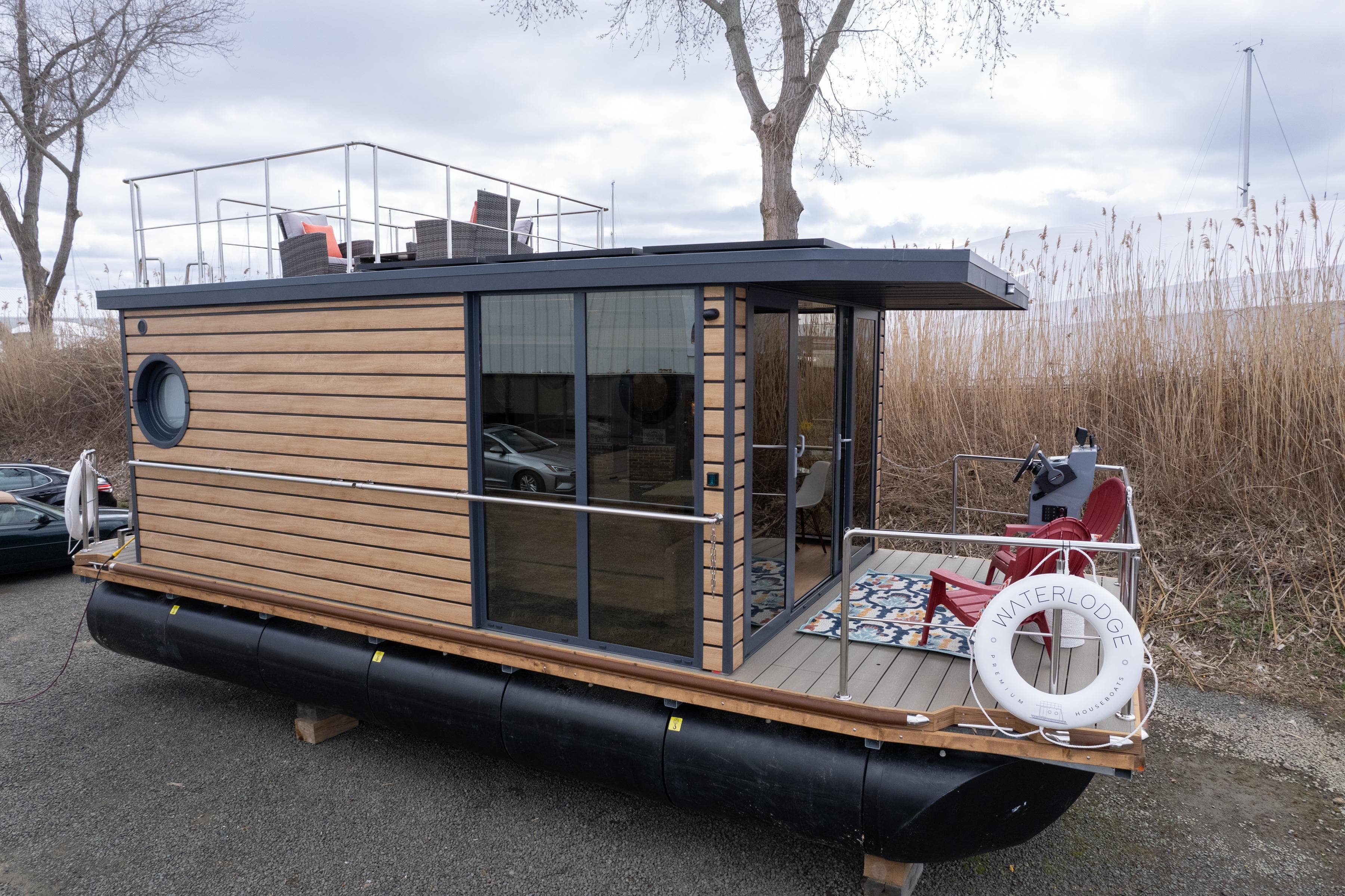 Modern 2024 Waterlodge Apart M houseboat with wooden exterior and rooftop seating.
