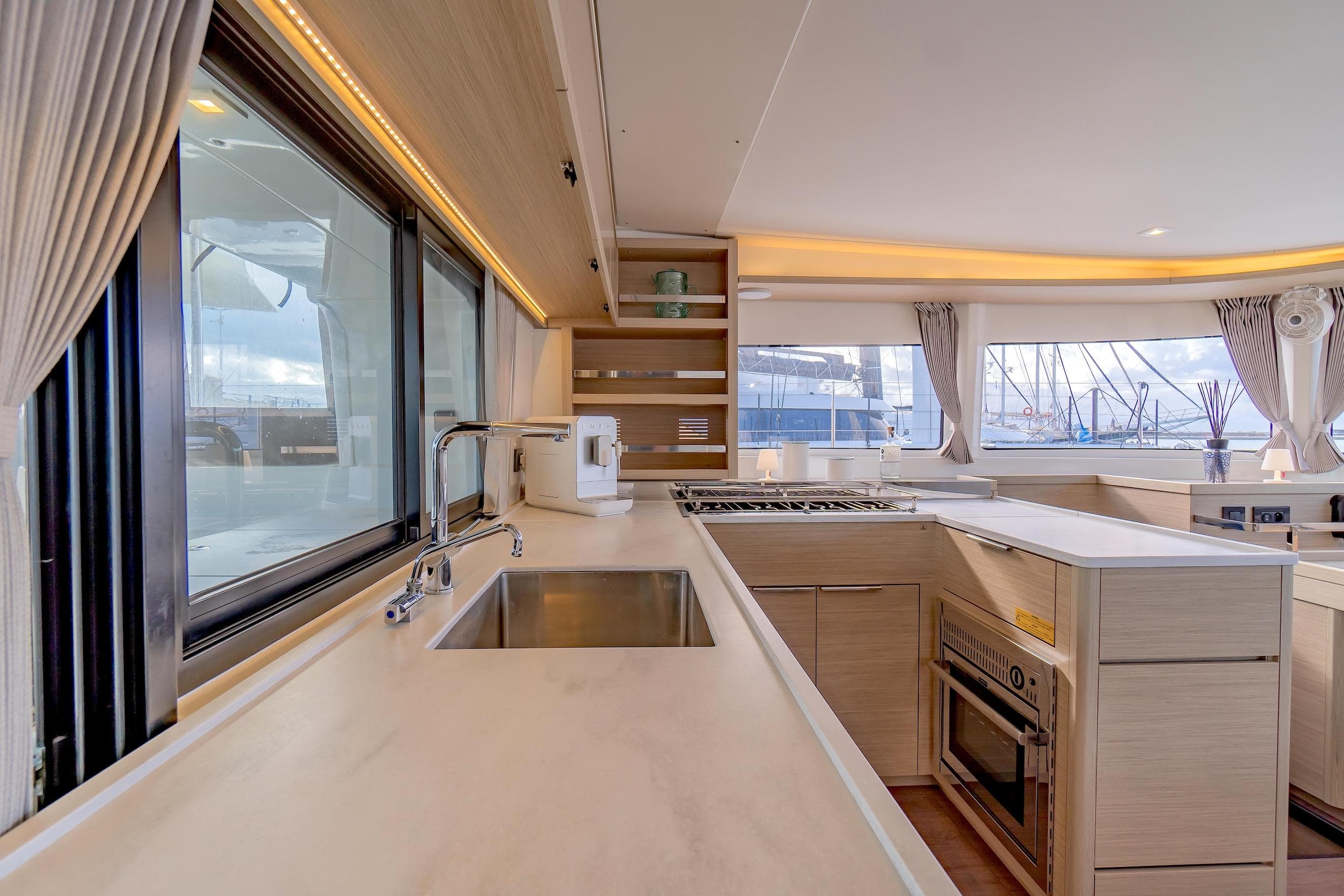 Luxurious interior of 2023 Lagoon 46 yacht with modern kitchen and large windows.